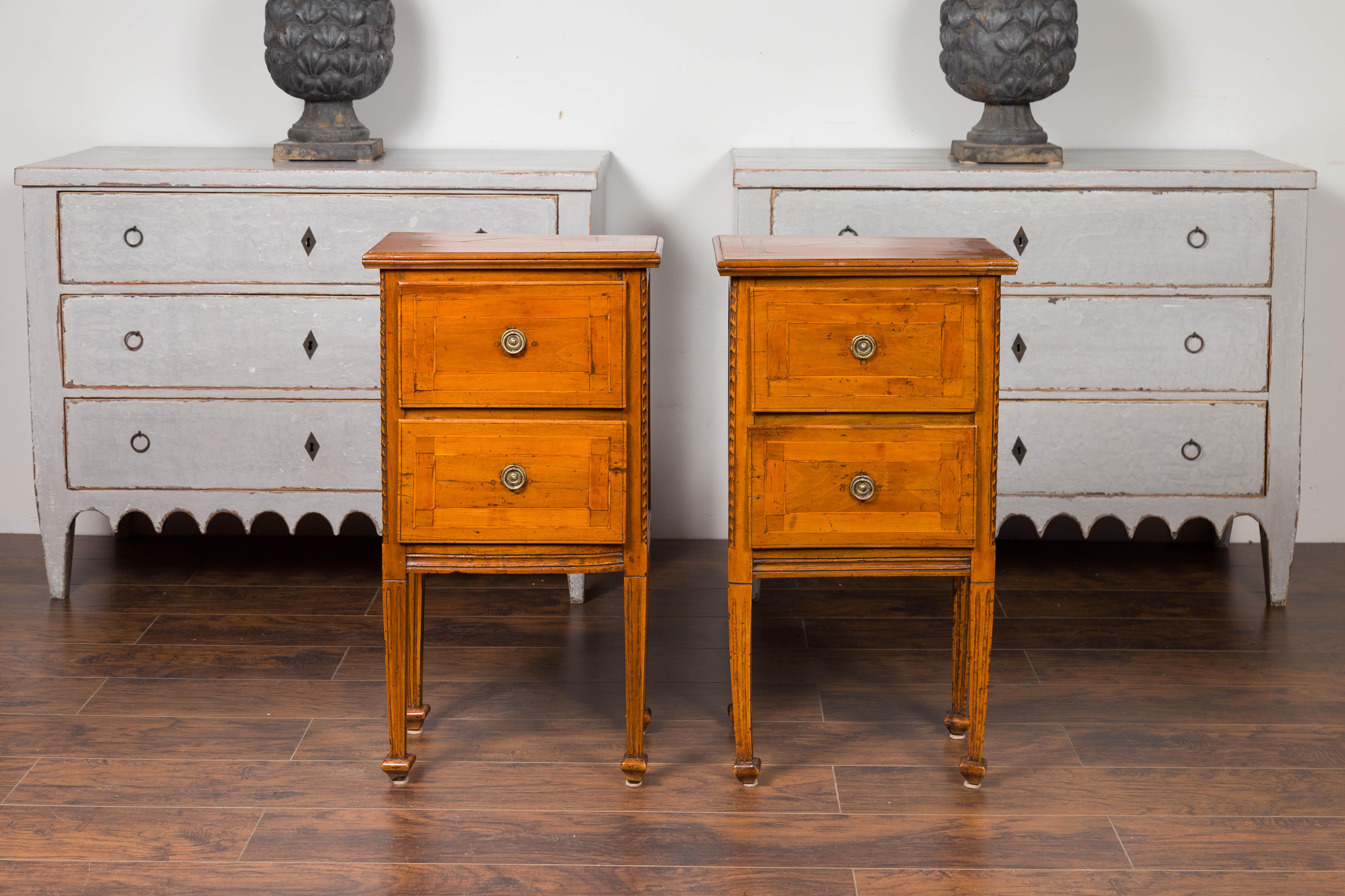A pair of Italian neoclassical walnut bedside tables from the early 19th century, with banding and fluted tapering legs. Born in Italy during the first quarter of the 19th century, each of this pair of bedside tables features a rectangular top