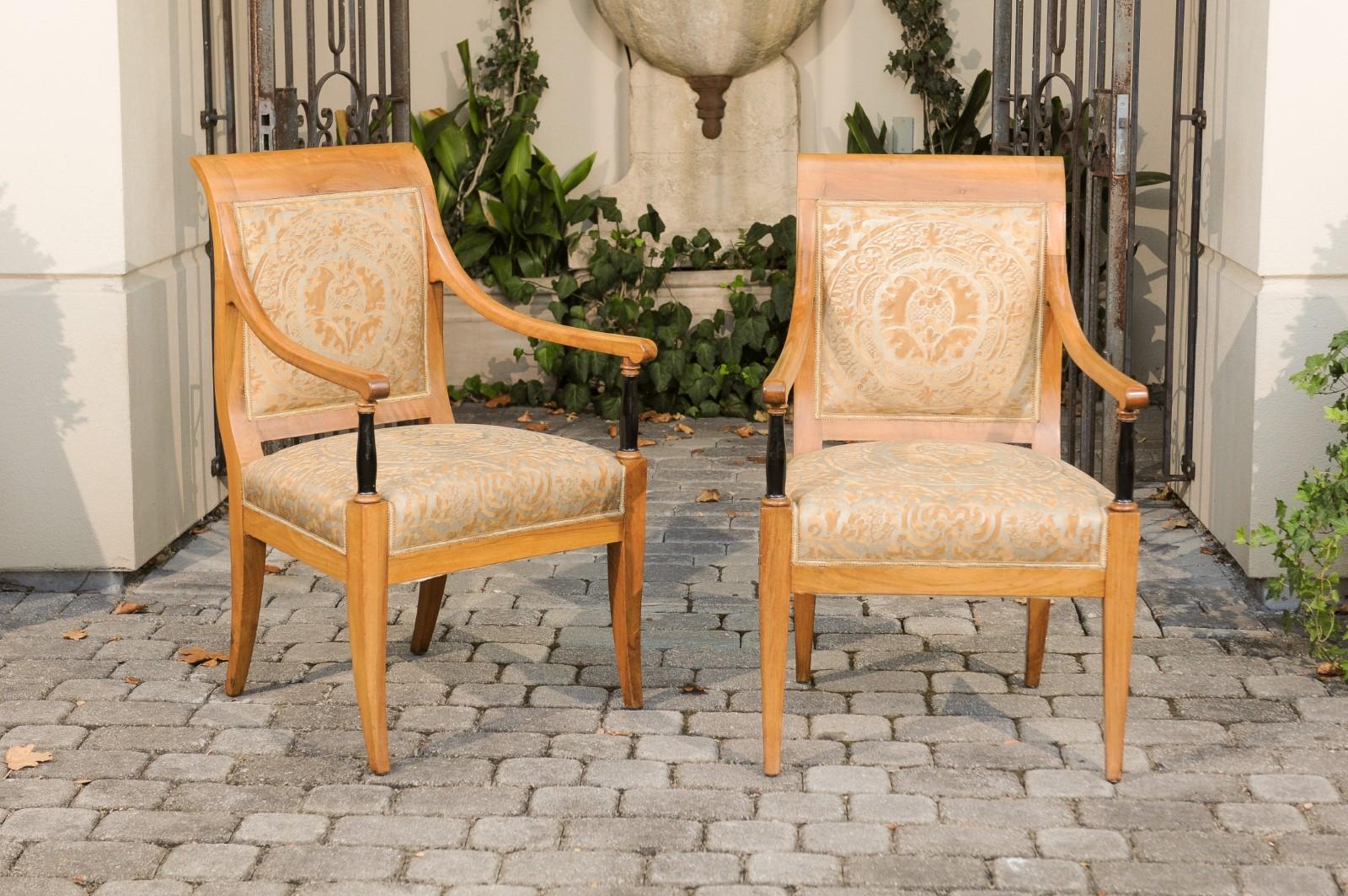 A pair of Austrian Biedermeier period armchairs from the mid-19th century, with Fortuny fabric and ebonized columns. Born in Imperial Austria during the first half of the 19th century, each of these Biedermeier armchairs attracts our attention with