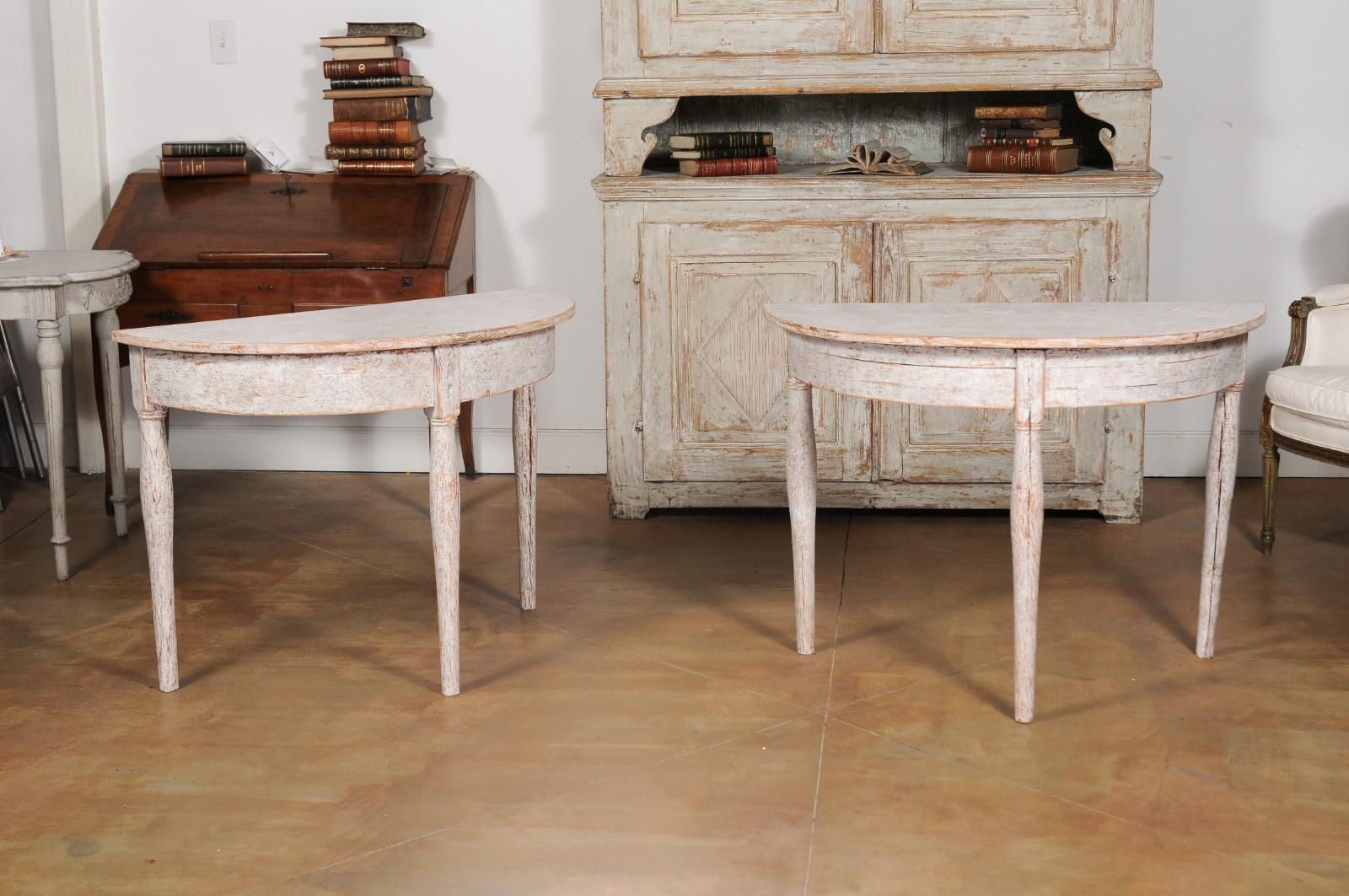 A pair of Swedish painted wood demilune console tables from the mid-19th century, with distressed finish. Born in Sweden during the first half of the 19th century, each of this pair of demilune tables features a semi-circular top sitting above a