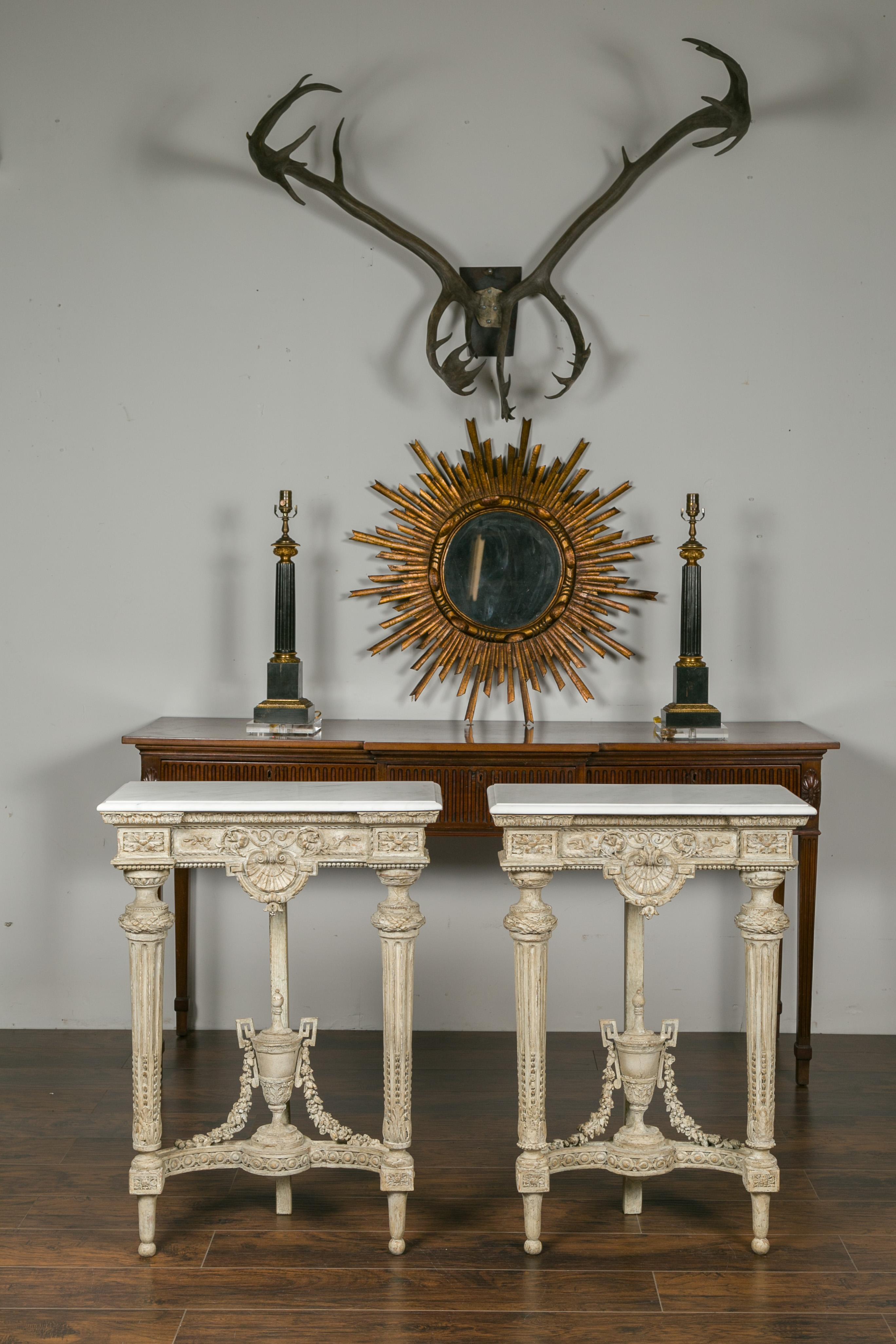 A pair of French Napoleon III period console tables from the late 19th century, with white marble tops, carved floral décor and refreshed paint. Born in France at the end of Emperor Napoleon III's reign, each of this pair of painted wood console