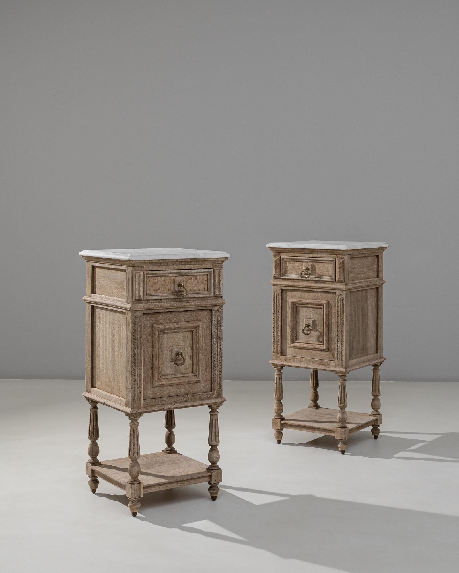 Questa coppia di comodini francesi Luigi XVI del 1890 offre un'elegante miscela di struttura neoclassica e fascino leggermente invecchiato. Ogni tavolo presenta un piano in marmo bianco con delicate venature, che poggia su un unico cassetto ornato