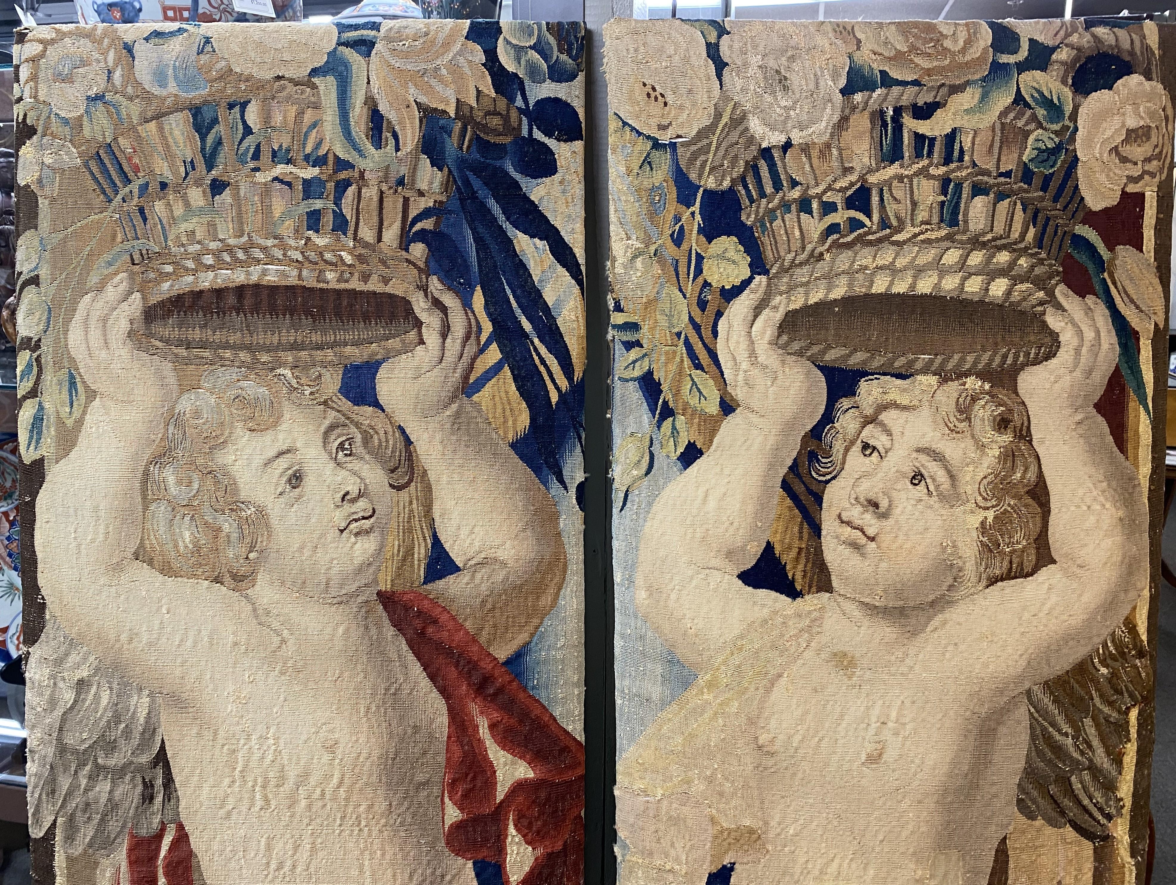 Pair of Brussels tapestry fragments finely woven of silk and wool featuring angels or putti carrying a basket of flowers above their heads. Opposing angels, one with a gold draped cloth the other with a red cloth. Probably Belgium in origin, circa