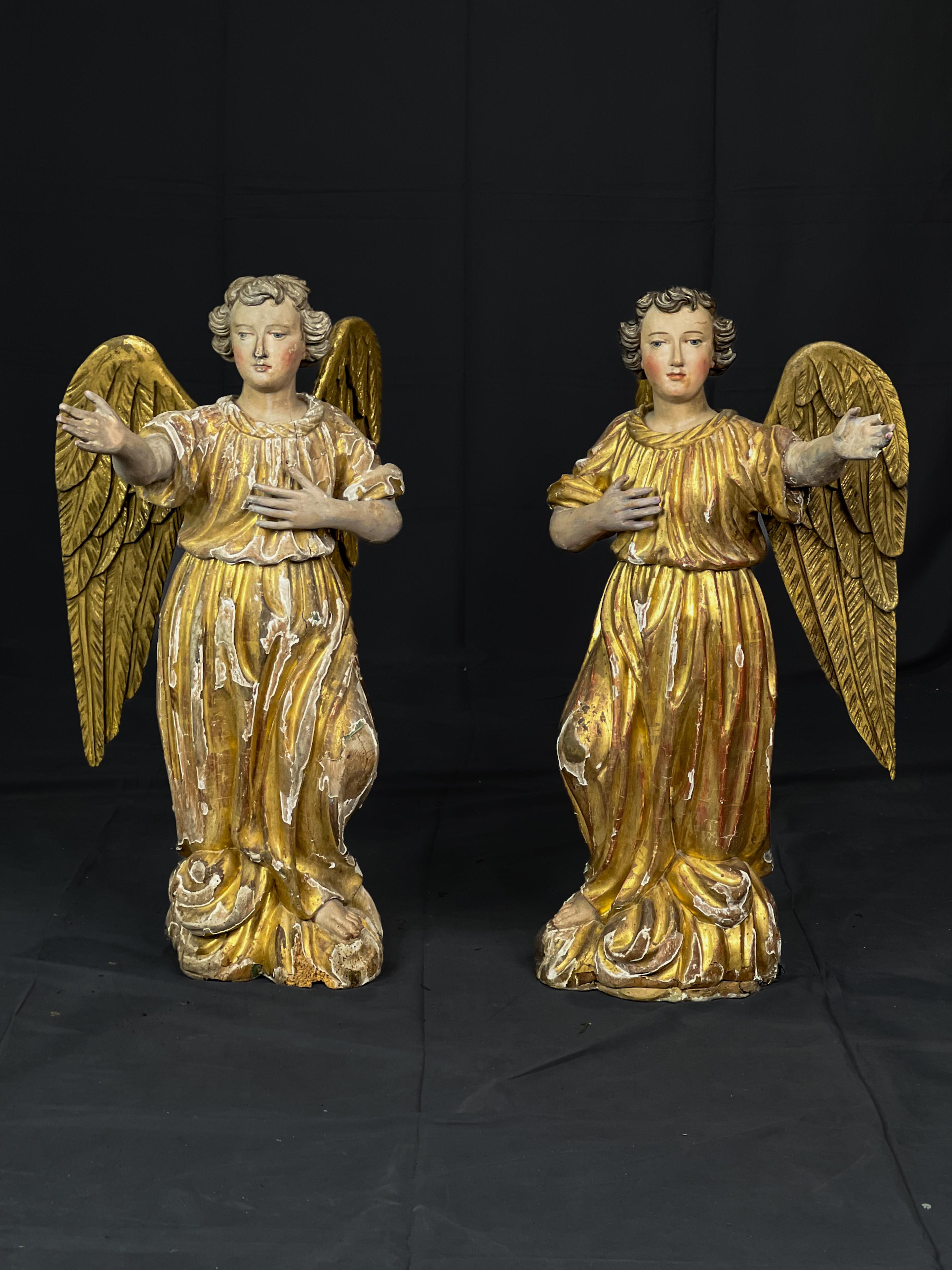 Pair of 18th c. Carved Wood French Angels that have gilded full length robes and wings. The pair have beautiful hand painted facial details. The back of each statue has a metal brace to help support the wings.