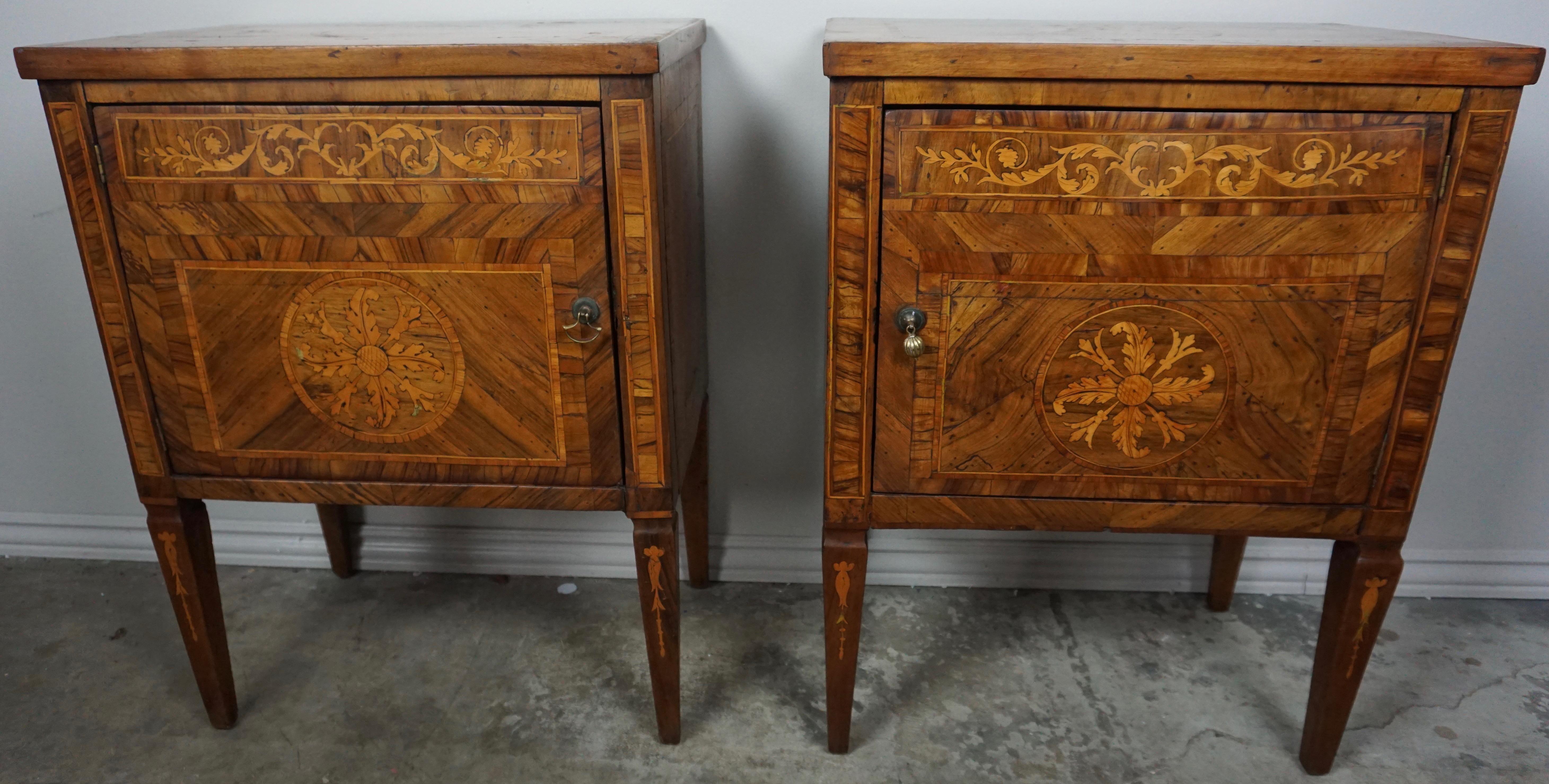 Pair of 18th century Italian inlaid chests that stand on four straight tapered legs. The chests are made up of various woods including walnut, maple & mahogany. The doors open to expose storage behind with a single shelf. The hardware does appear to