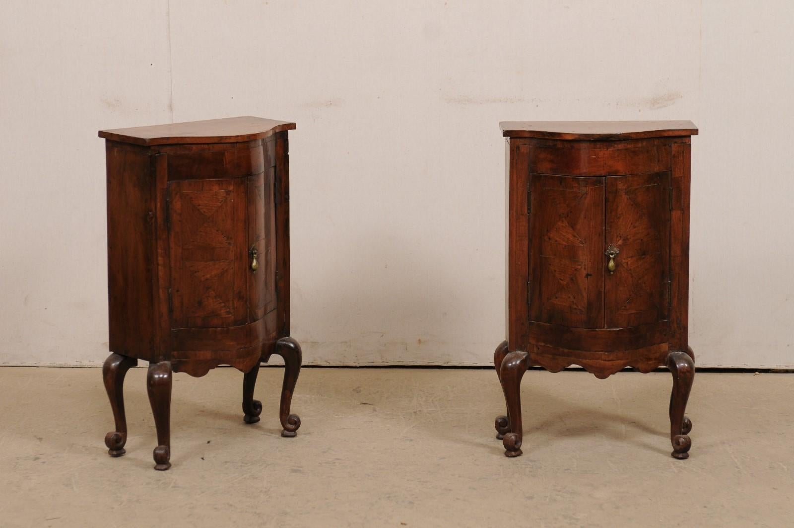 An Italian pair of small-sized, raised side chests with bowed fronts from the late 18th century. This sweet pair of antique cabinets from Italy are created from walnut wood and feature a shapely bowed front, with carcase which houses two curved