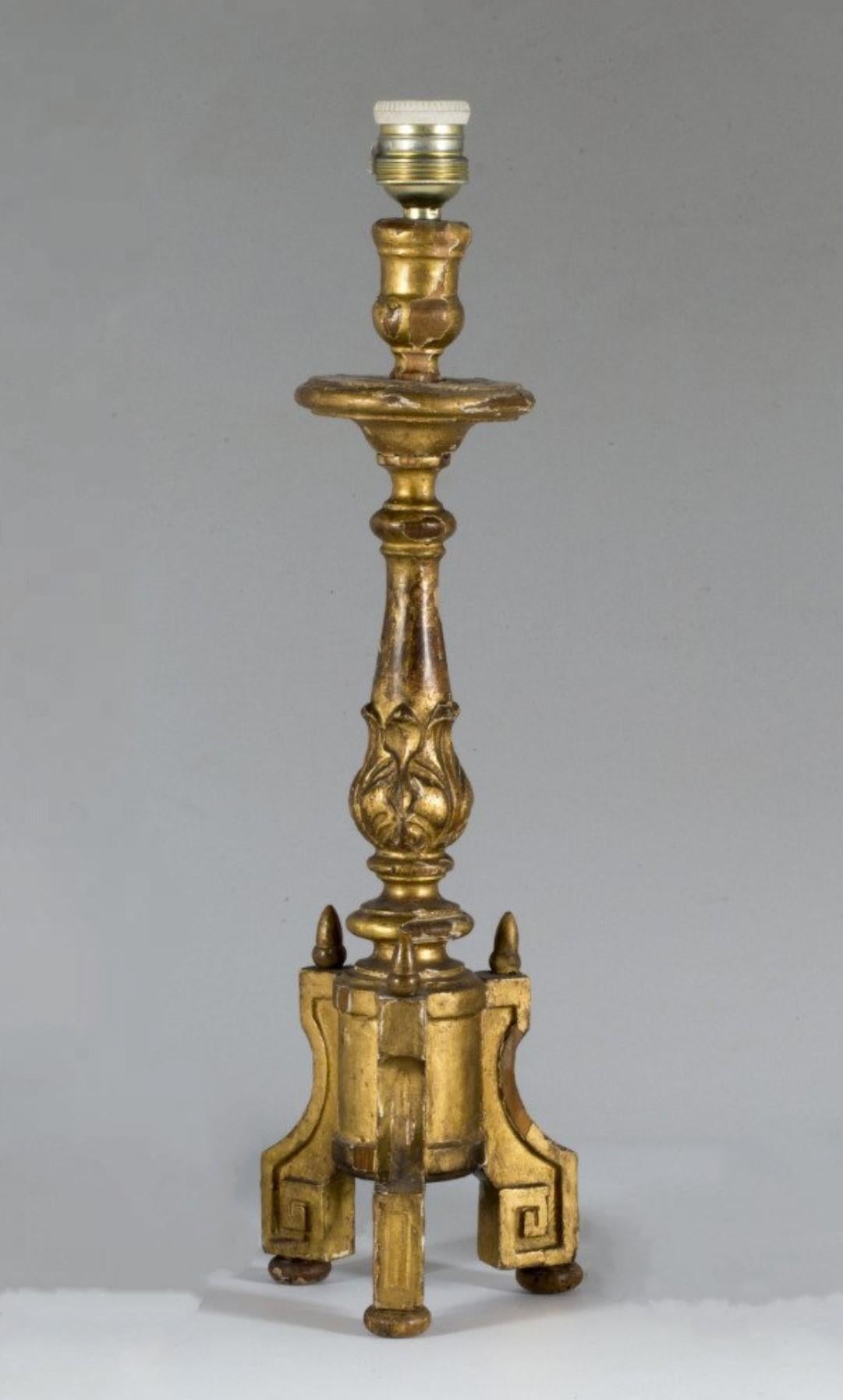 A wonderful pair of wooden altar candlesticks converted to table lamps, Spain, mid-18th century. Hand-carved decorate with acanthus leaf motivs on richly elaborate tripod base and gold leaf gilding over gesso, with new of-white lamp shades. These