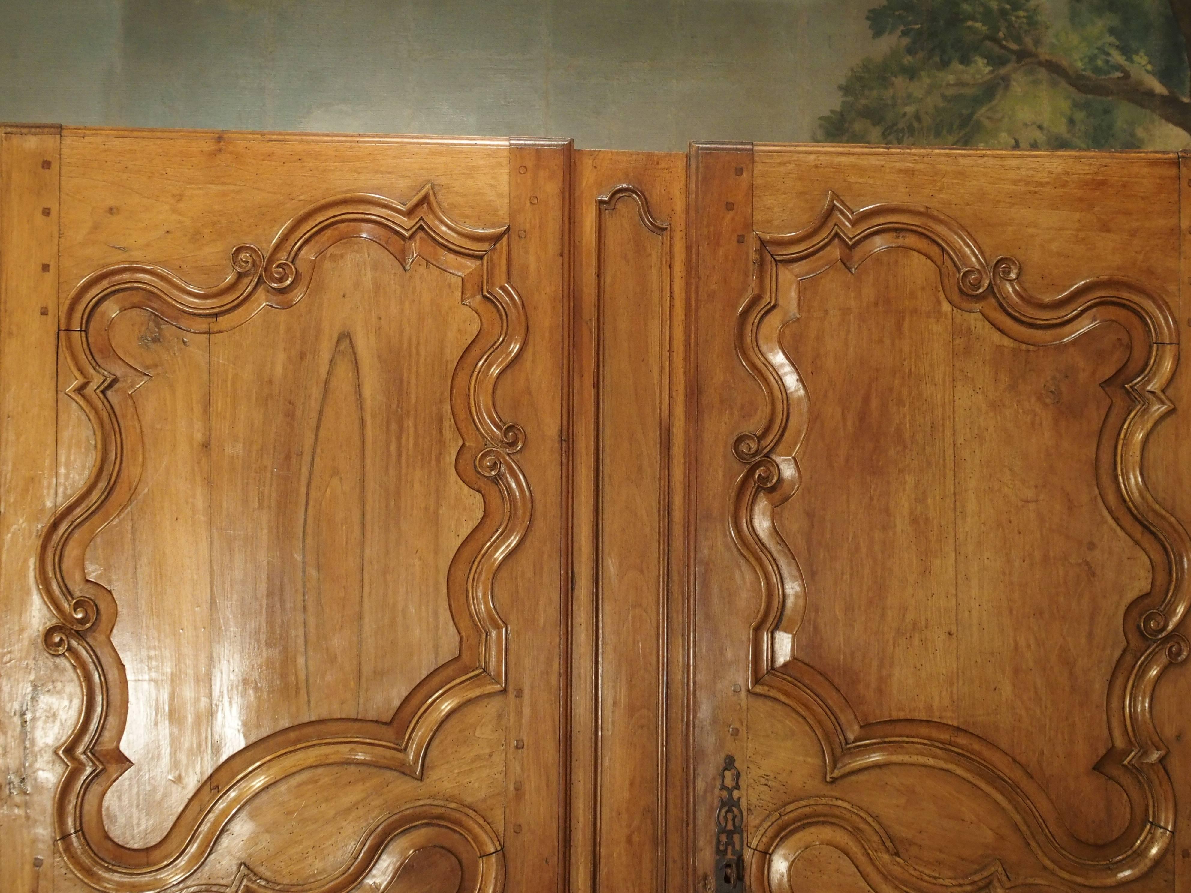 These elegant and refined armoire doors come from Arles, France. They once graced a beautiful armoire that was made in the 1700s. Their ornamentation on the three raised beveled panels, consists of linear C and S scrolls, and asymmetrical outlines