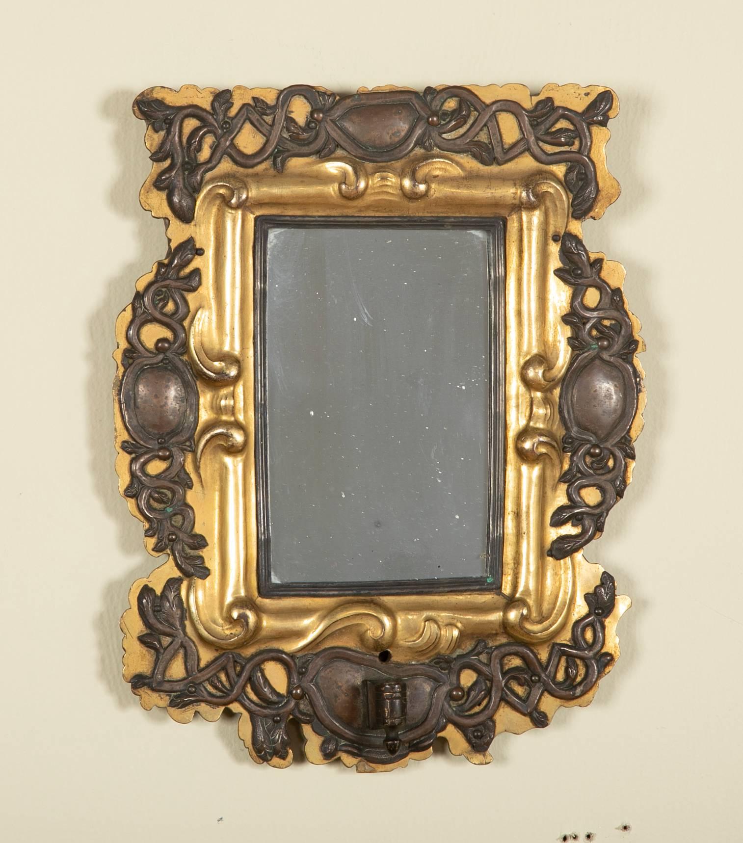 Pair of unusual Baroque Baltic or possibly Russian mirrors that were originally sconces. With silver arabesques overlaying gilt brass frames mounted on oak. The holders for candle arms still mounted on what are now a wonderfully unique pair of small