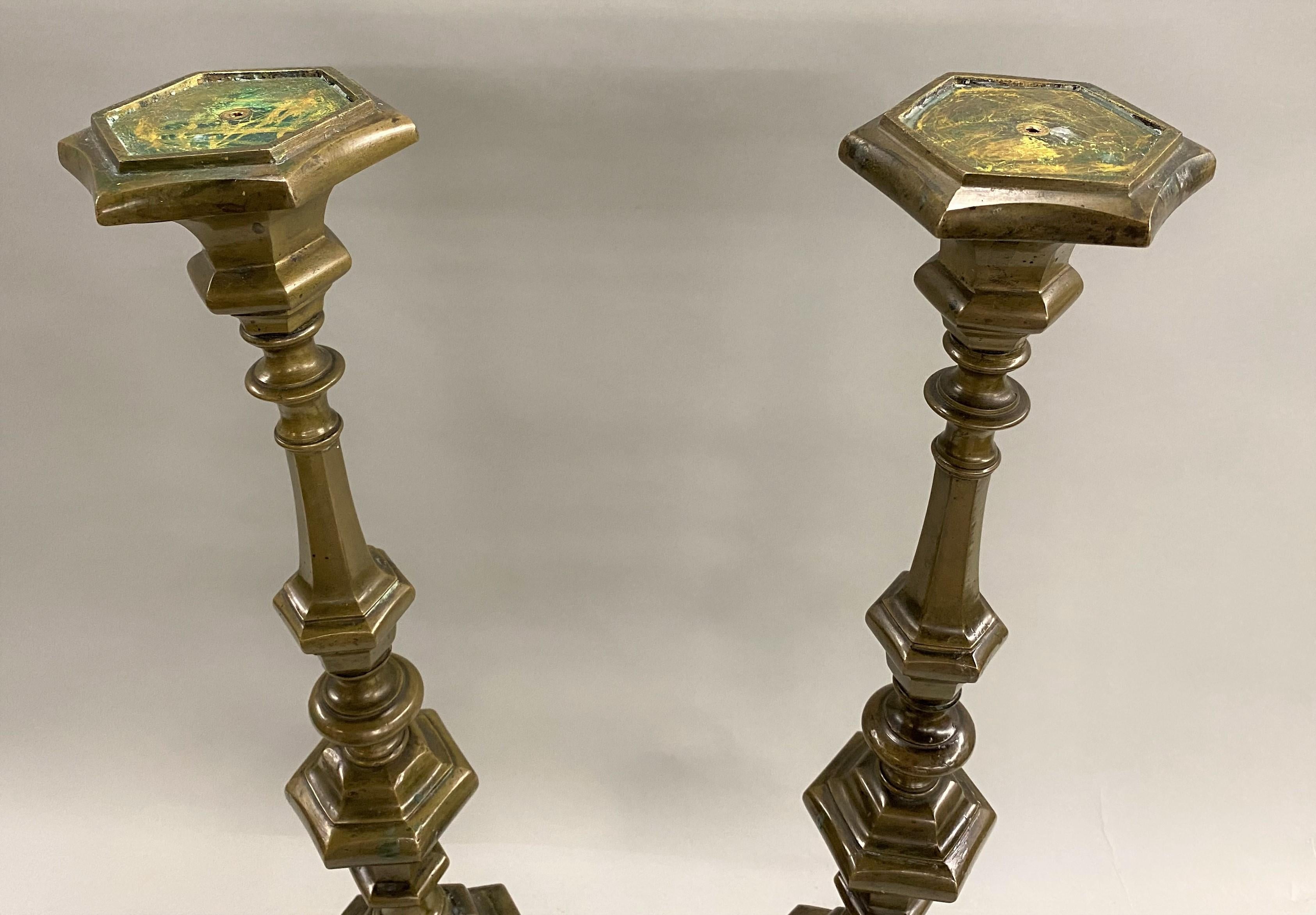 An impressive pair of Baroque style patinated bronze candlesticks with baluster form stem and tripod feet, Continental in origin (possibly Italian) dating to the 18th century, converted to lamps in the 20th century. The wiring and lamp fittings have