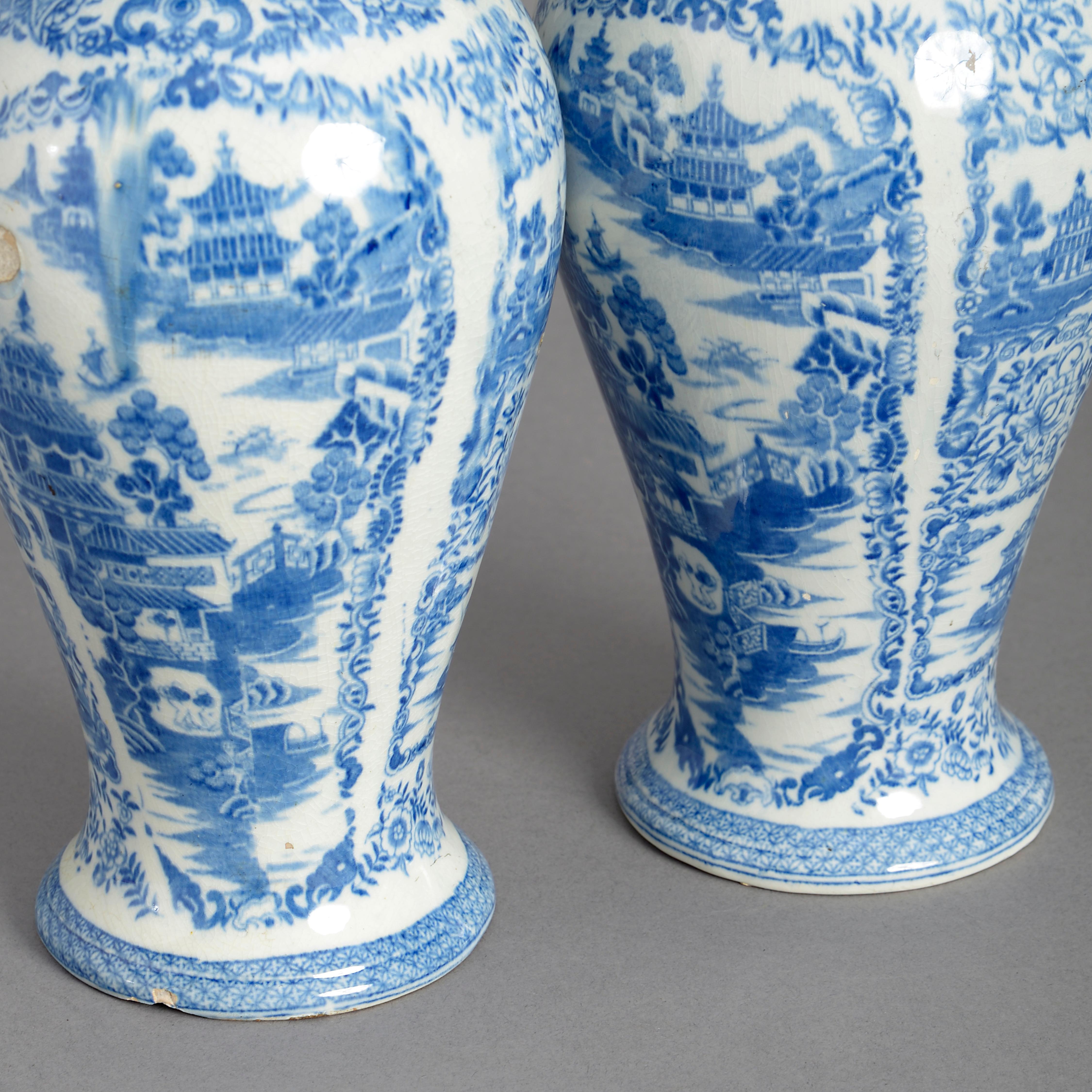 A pair of late 18th century blue and white glazed Staffordshire pottery baluster vases and covers, decorated throughout with chinoiserie.

One neck restored. One vase with period firing mistakes to the body.