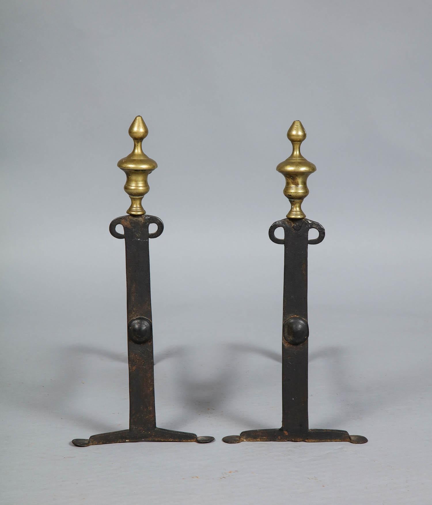 Fine pair of 18th century classical andirons having brass urn finials over flattened bar shafts with open Curule shoulders and standing on flattened penny feet, circa 1780. Possibly Rhode Island.