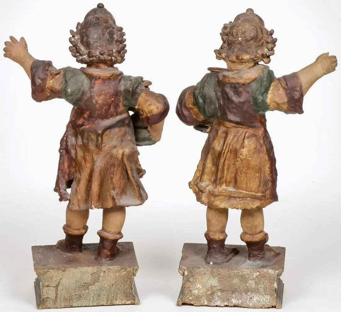 Pair of 18th Century Candle Bearing Angels.
Comprising a pair of charming carved polychrome and gilt wood figural candlestands modeled as angels and on integral raised stands, carved in full round and with gesso stiffened clothing. 
Decorate a