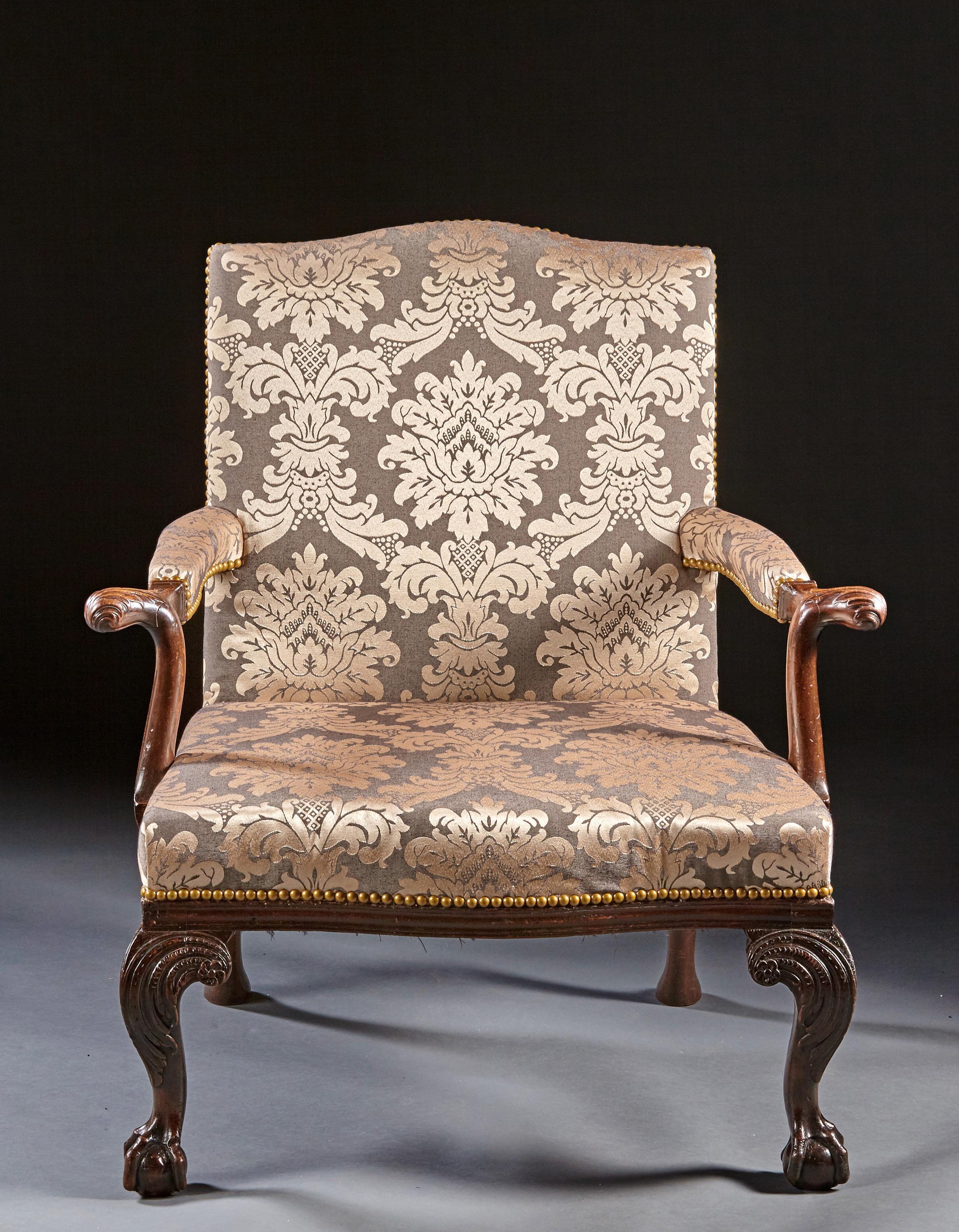 A pair of carved mahogany Chippendale gainsborough chairs with ball and claw feet, acanthus carved knees and raked cabriole rear legs ending in padded feet. The backs with cupids bow crest and with openarms and leaf carved handles are supported by