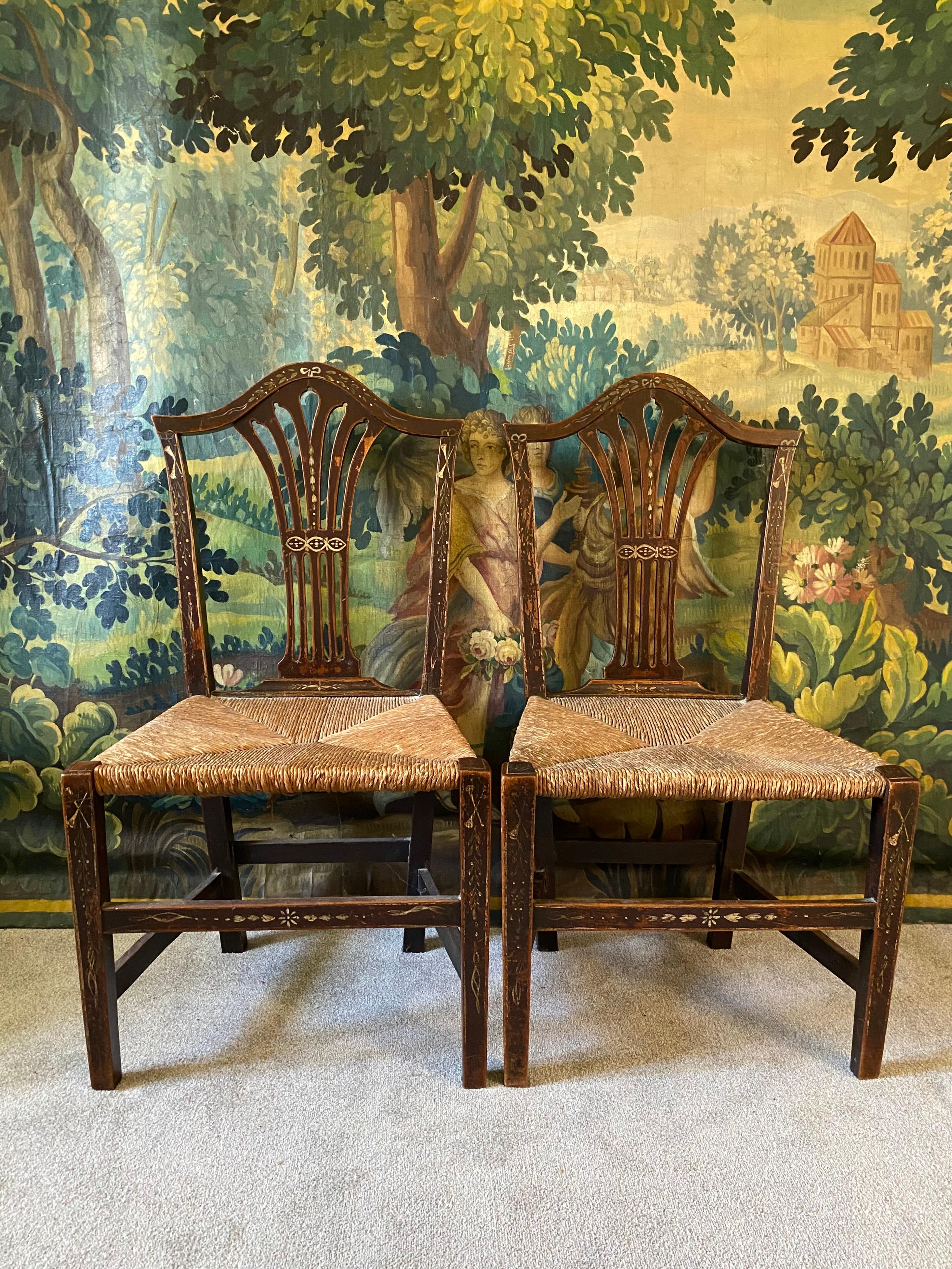 A good pair of 18th century mahogany side/ dining chairs in a style closely associated with George Heppelwhite - these have charming hand painted decoration and thick rush seats and are offered in good condition - they are strong and stable suitable
