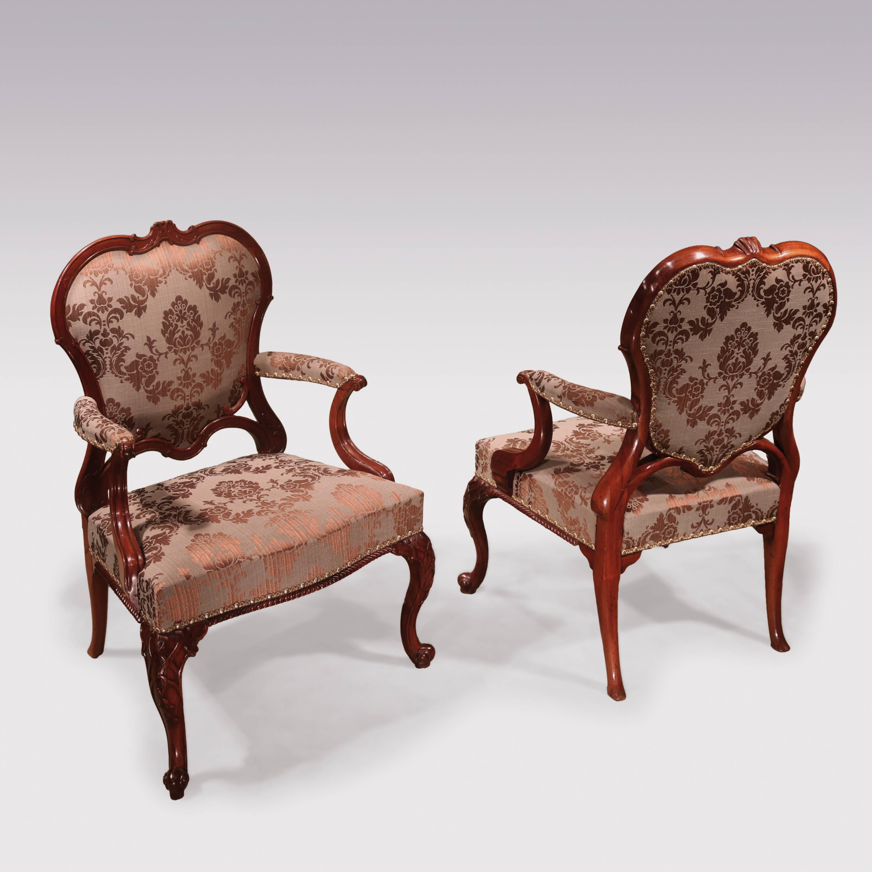 An important pair of mid-18th century Chippendale period mahogany Library Armchairs, having unusual carved and scrolled cartouche-shaped backs, with scroll moulded set-back arms. The Chairs having stuffover seats with gadrooned borders, supported on