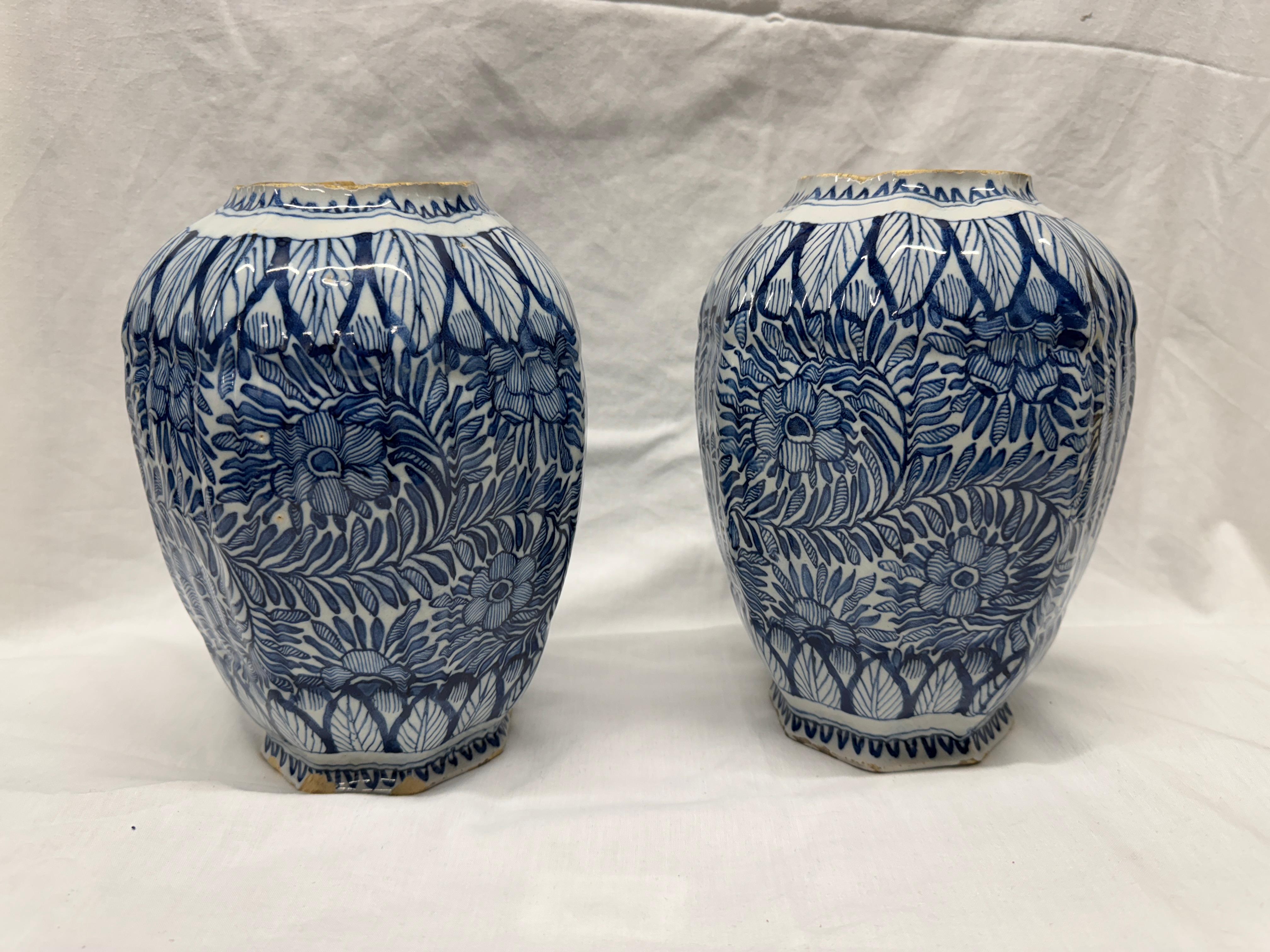 Pareja de tarros de bulbos de Delft del siglo XVIII, de forma ovoide octogonal pintados en azul con loto en volutas dentro de bordes de hojas.