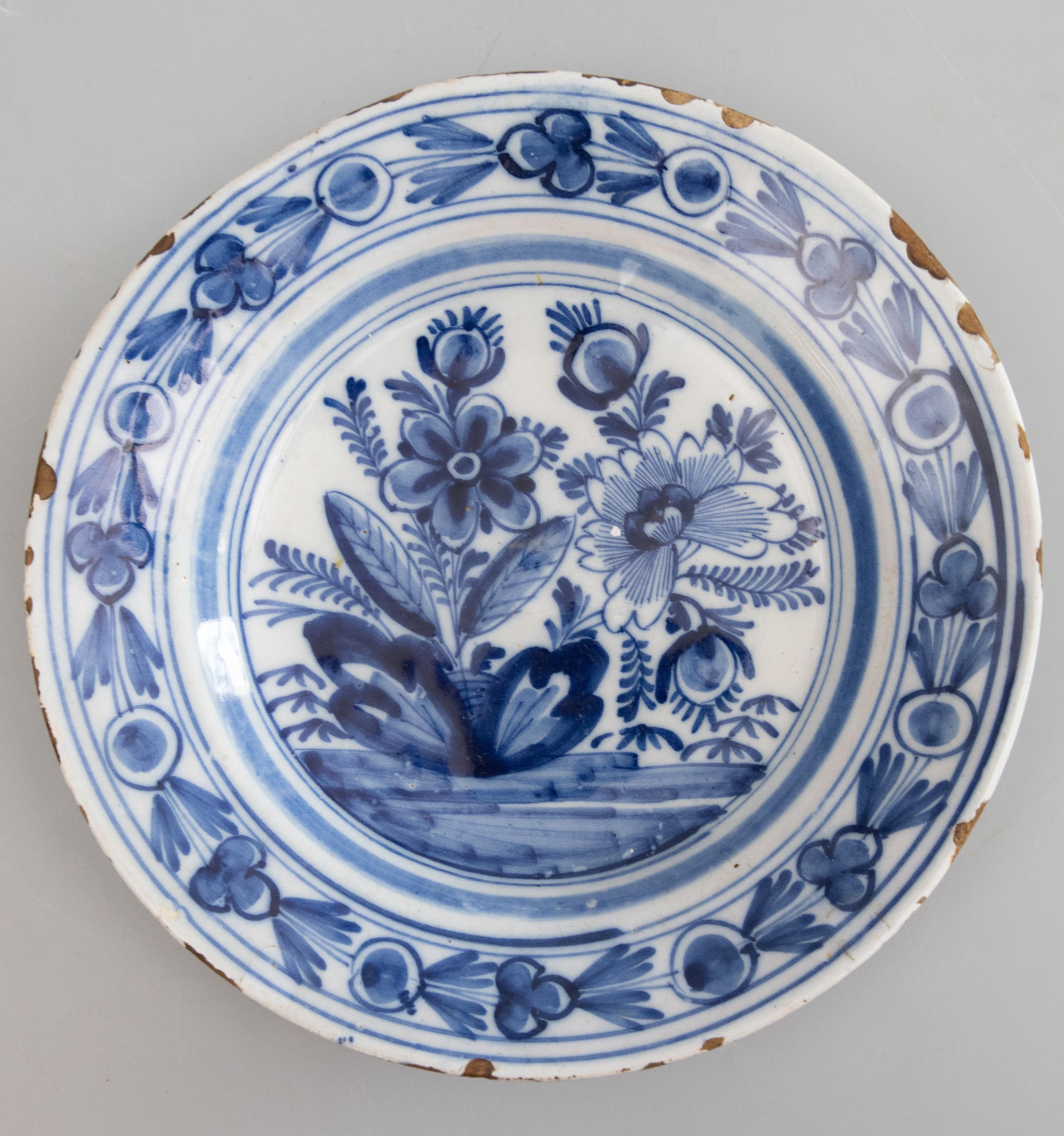 Paire d'assiettes anciennes en faïence de Delft hollandaise du 18e siècle, ornées de fleurs de différentes sortes, entourées d'un motif floral sur le pourtour. 