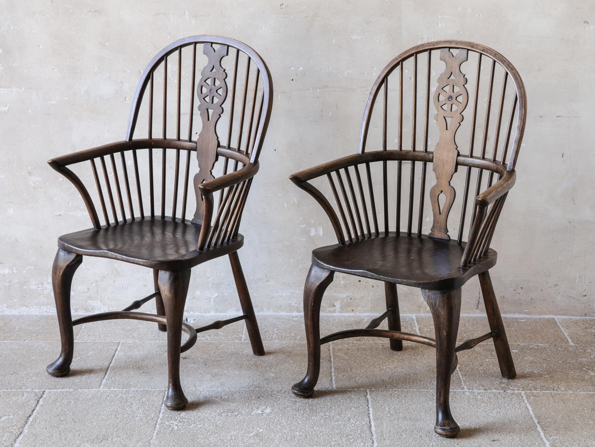 Una splendida coppia di poltrone Windsor del XVIII secolo, realizzate in pregiato legno di olmo. Queste sedie vantano un design raro ed elegante, con gambe a cabriole che terminano graziosamente con i classici piedi a pad. La finitura a cera marrone