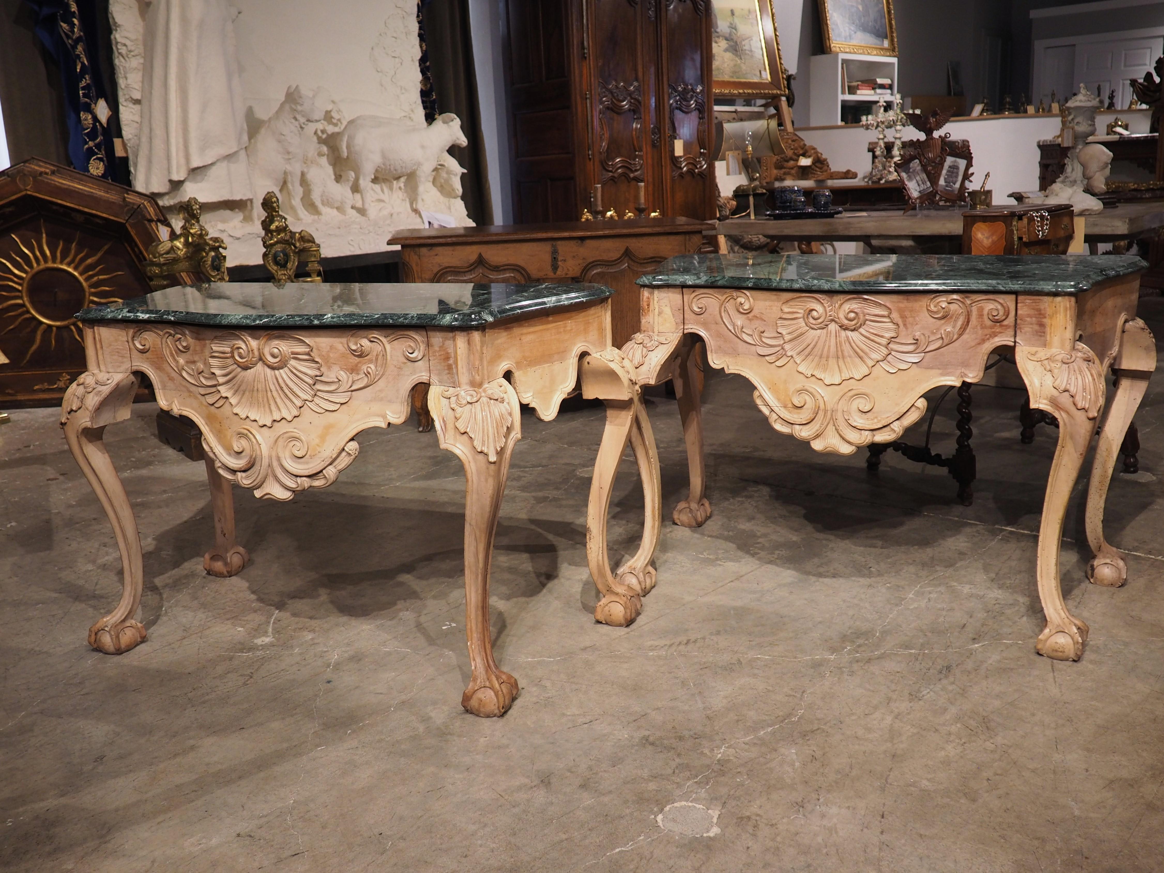 This handsome pair of English ball and claw console tables, from the 1700’s, are fitted with shaped, green marble tops. The cabriole legs with feet that resemble a claw grasping a ball was a design element that was highly popular in the middle of