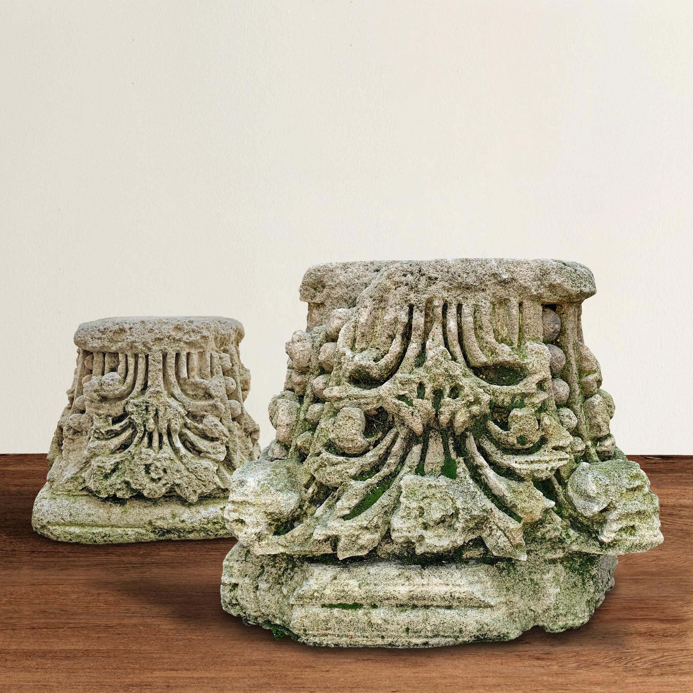 A pair of breathtaking 18th century English carved stone capitals of the Corinthian order with clusters of flowers, covered in moss, and in wonderful ancient 