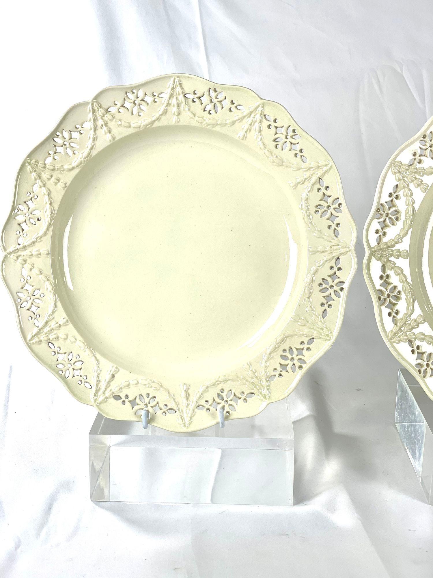 This pair of large 18th-century English pierced creamware dishes is both elegant and beautiful.
Made in England around 1785, the plates feature delicate diamond and dot piercing.
The border showcases twelve clusters of piercings, along with a