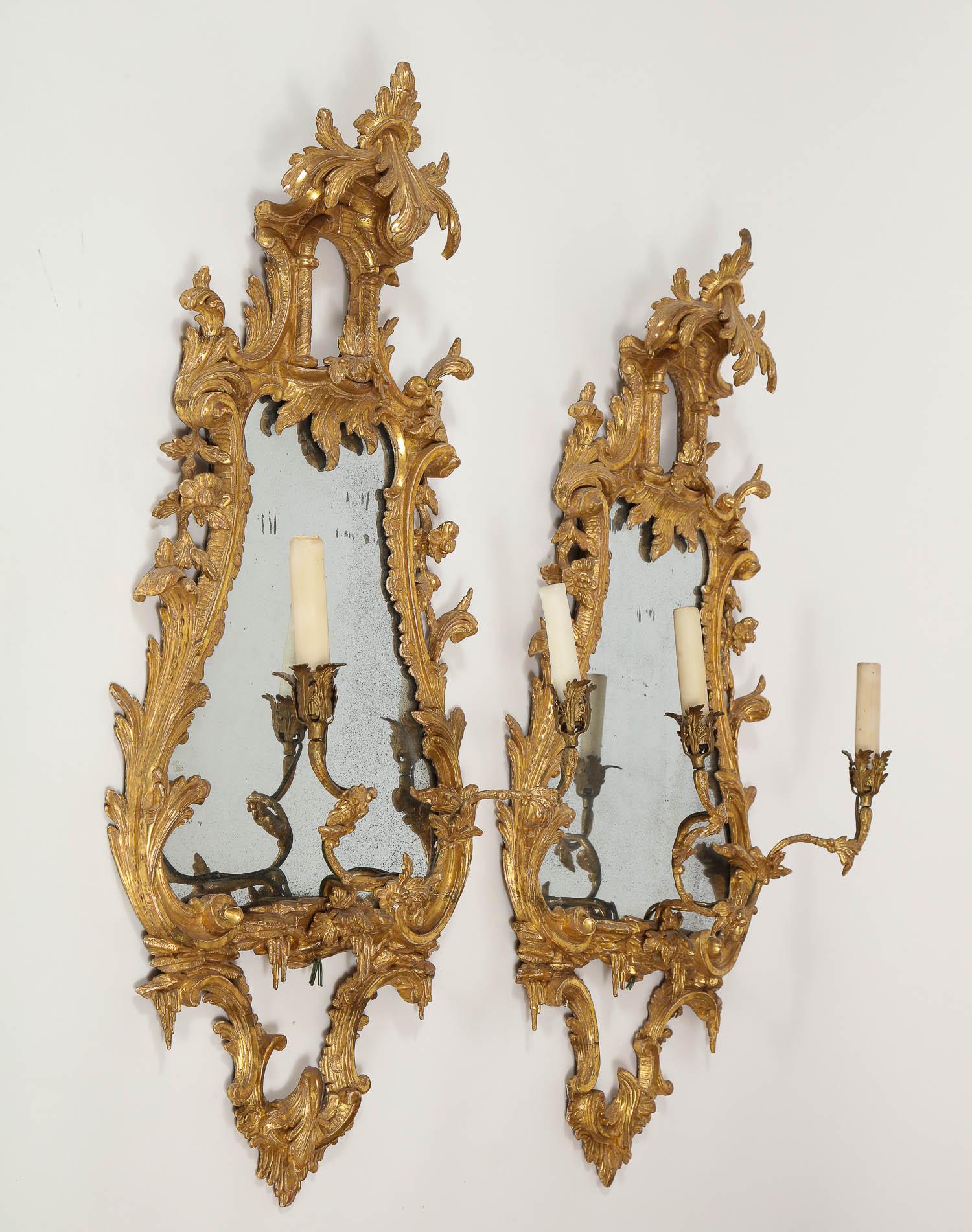 Belle paire de miroirs en bois doré sculpté de style chinoiserie anglaise du XVIIIe siècle avec chandeliers. Ces miroirs en bois doré magnifiquement sculptés à la main sont méticuleusement détaillés et ornés de feuilles d'acanthe fleurissant dans