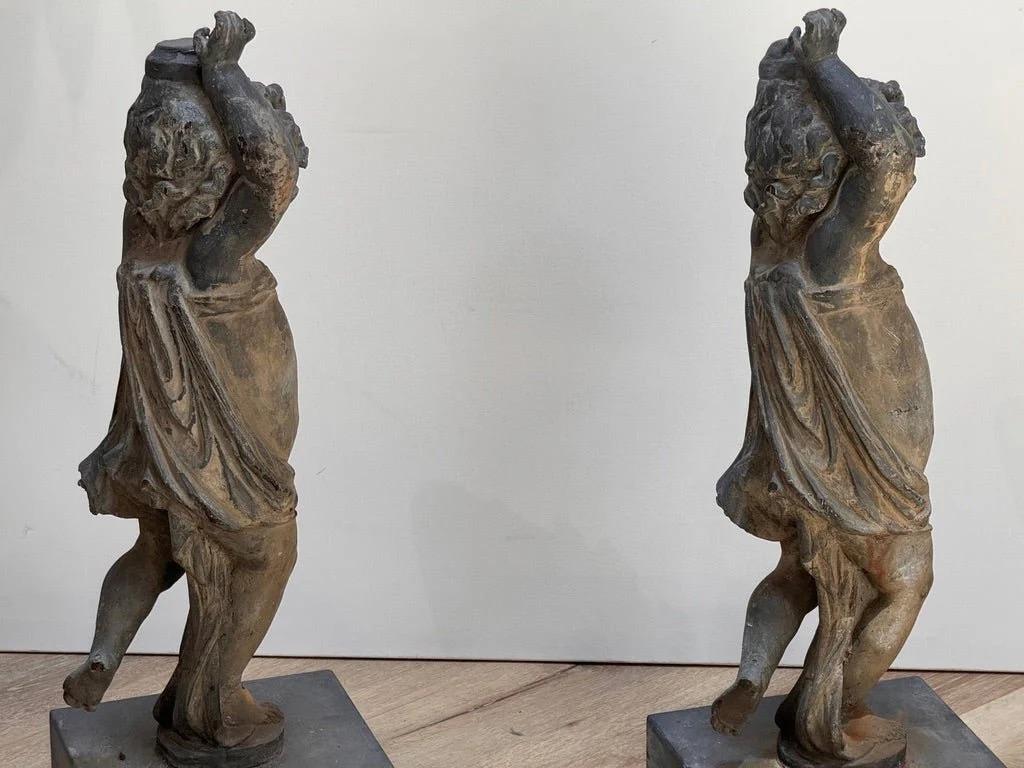 Coppia di putti in piombo inglesi del XVIII secolo, originariamente destinati a ornamenti architettonici o da giardino. Giovani putti drappeggiati in posizione contrapposta, ognuno dei quali tiene le braccia in alto: probabilmente un tempo