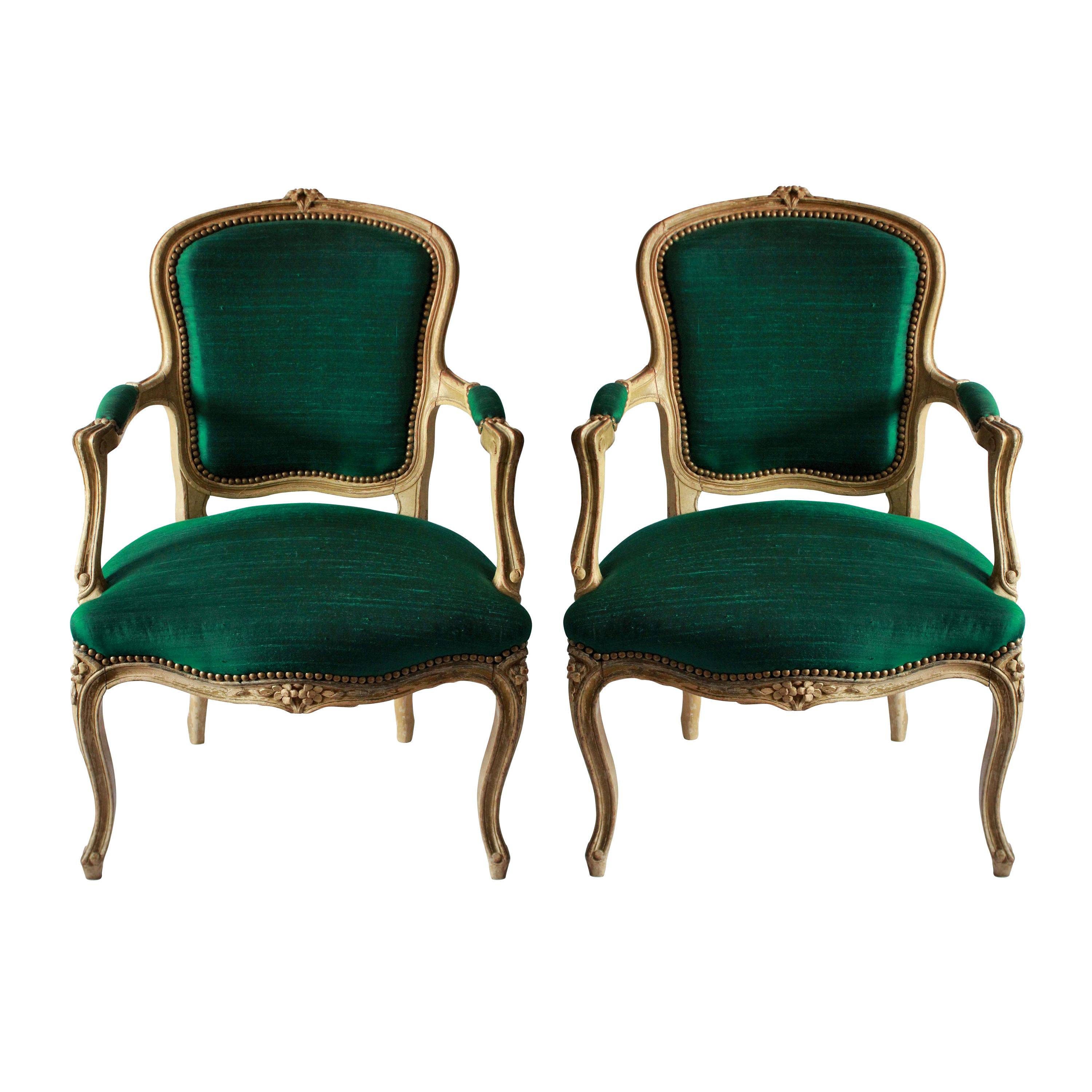 A pair of French 18th century distressed painted armchairs, newly upholstered in emerald green silk.
