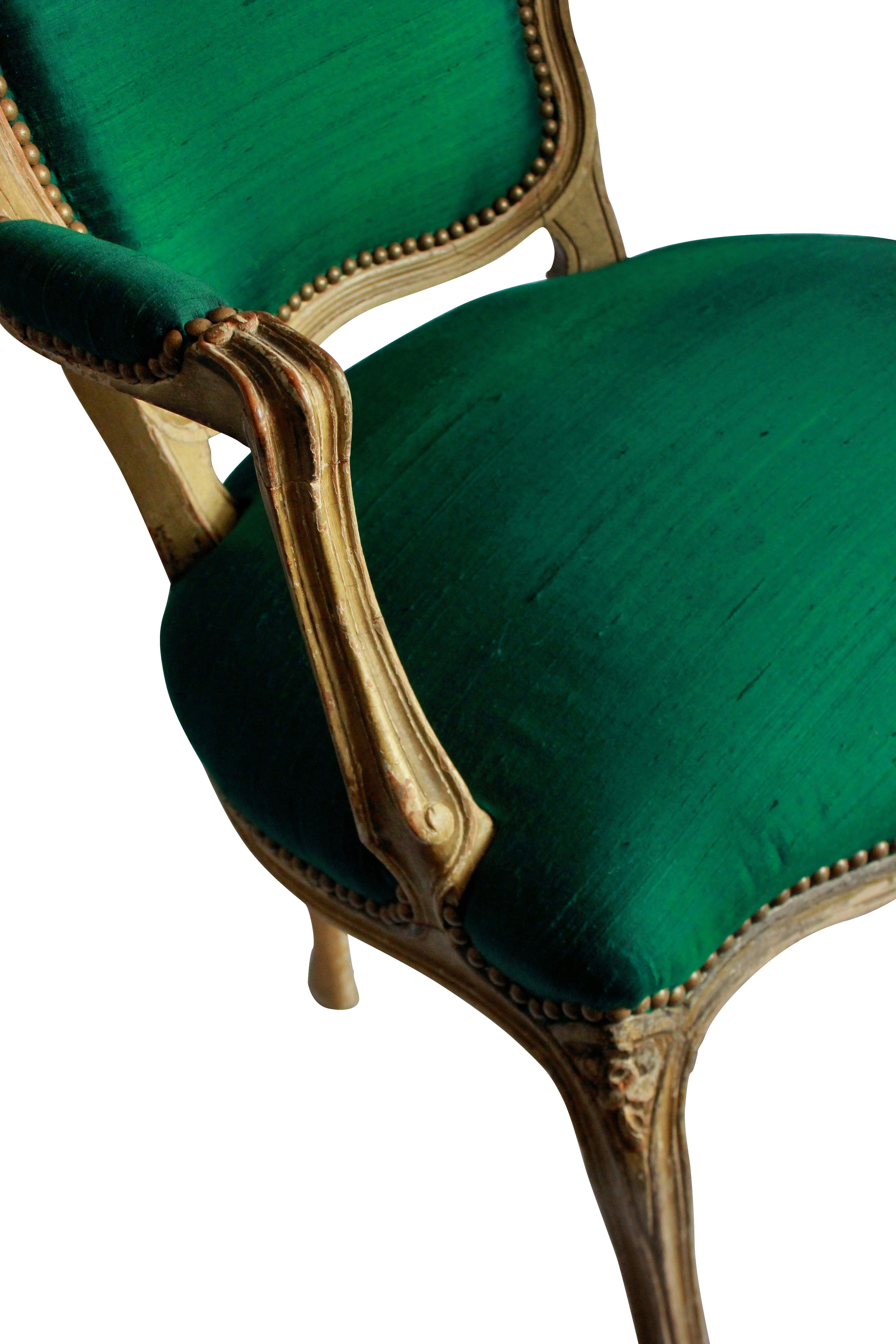 A pair of French 18th century distressed painted armchairs, newly upholstered in emerald green silk.