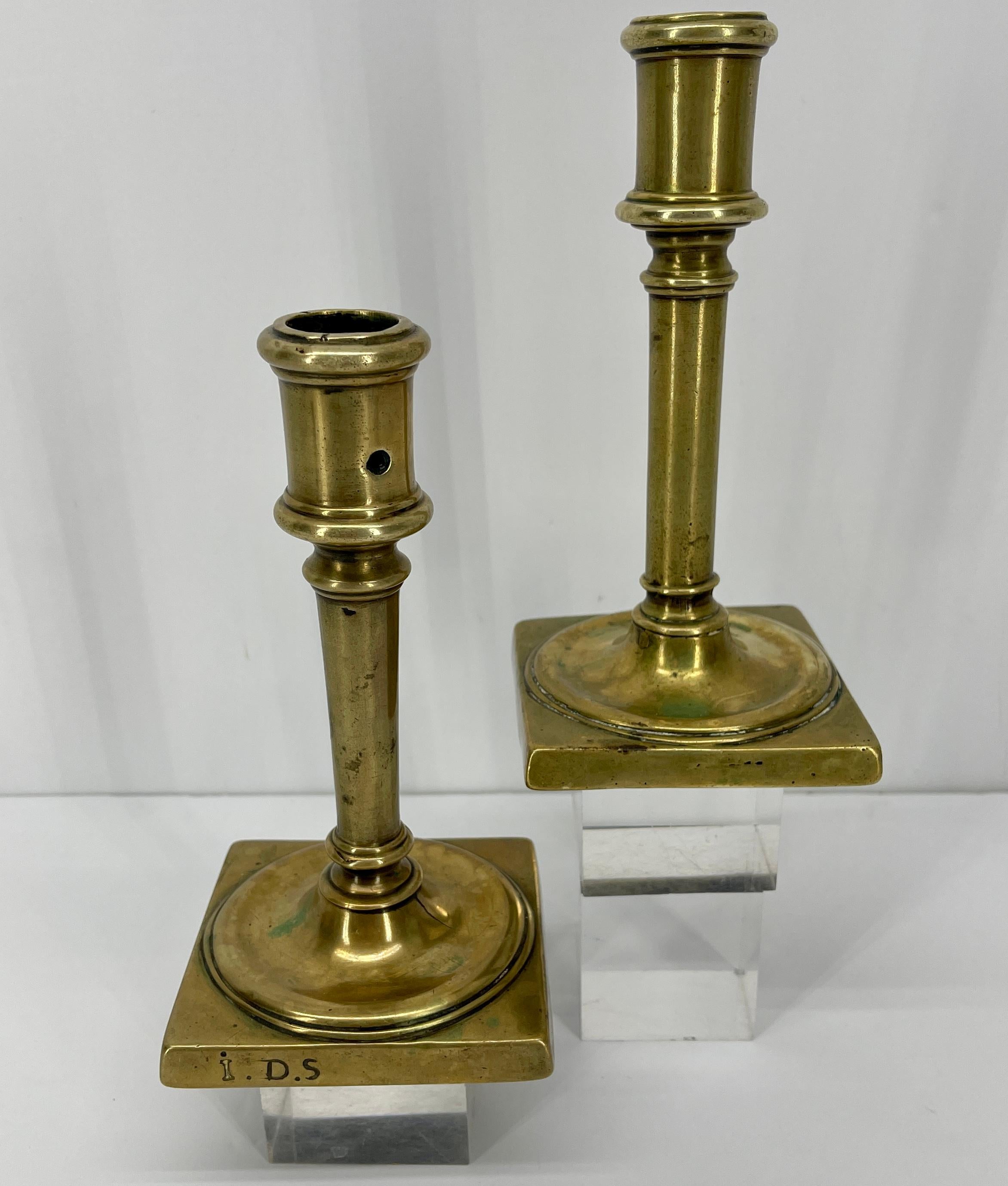 This fine pair of 18th Century brass candlesticks has a sturdy base supporting faceted stems and candle cups. Simply elegant period pieces; each candle cup has a hole for wax removal. In original vintage patina, the candle holders are a wonderful