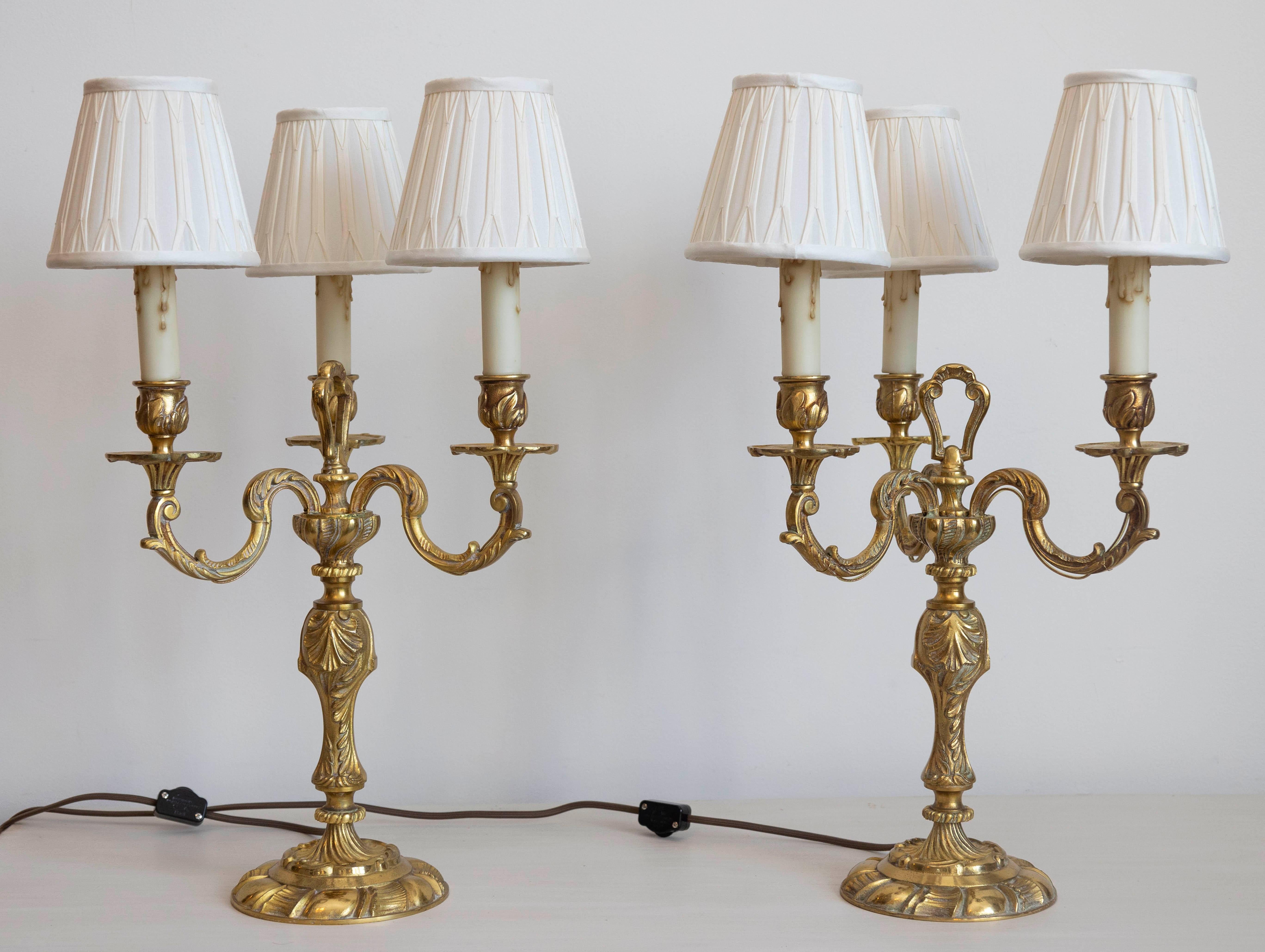 Esta exquisita pareja de candelabros franceses de bronce dorado del siglo XVIII, ahora convertidos elegantemente en lámparas de mesa, encarna la opulencia y la refinada artesanía del periodo Luis XVI. Cada candelabro presenta una estructura de
