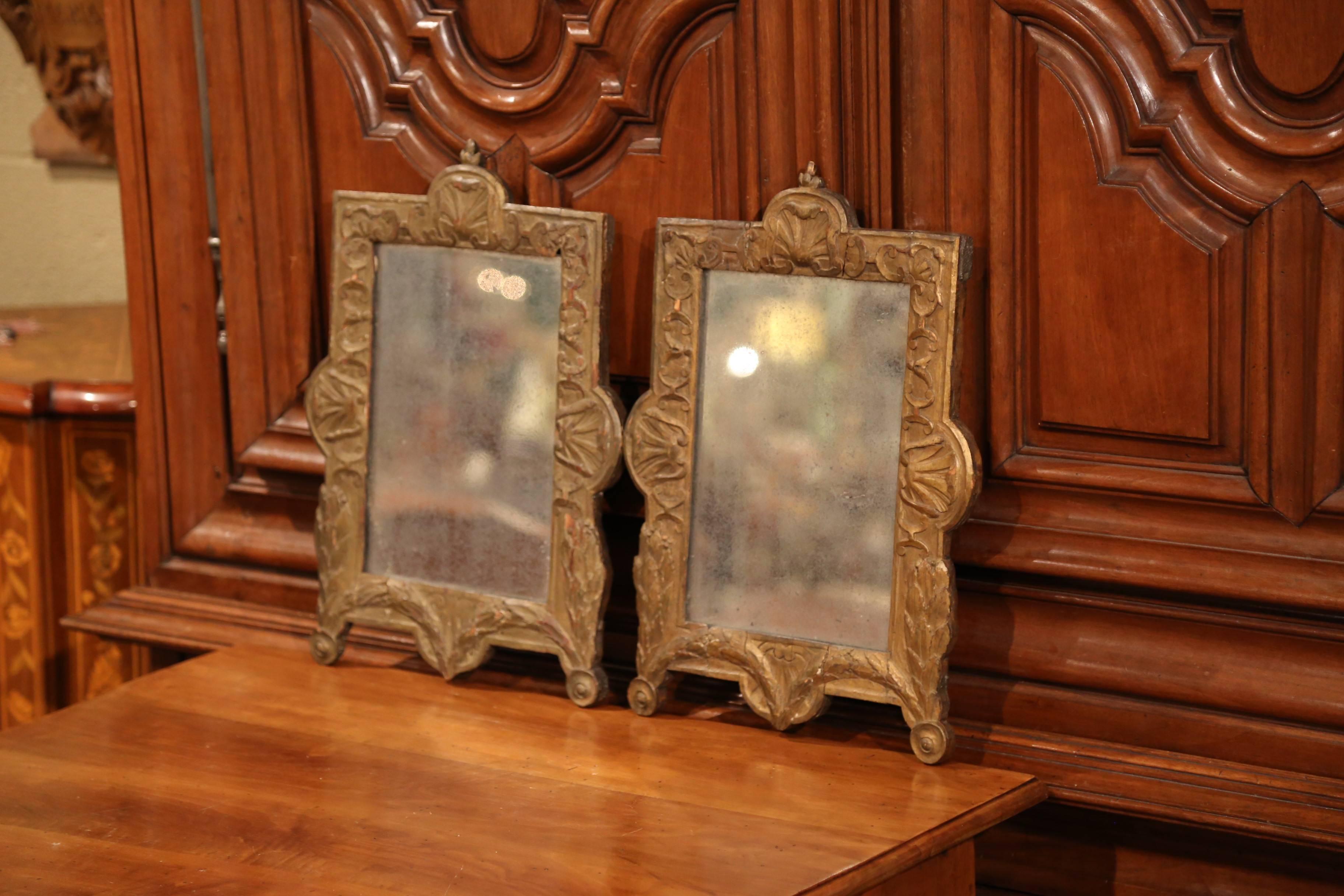 Elegant pair of antique wall mirrors from Southern France, crafted circa 1780, the fruitwood pieces feature hand carved motifs including shell at the pediment, decorative round feet at the base and laurel leaves on the sides. They also have the