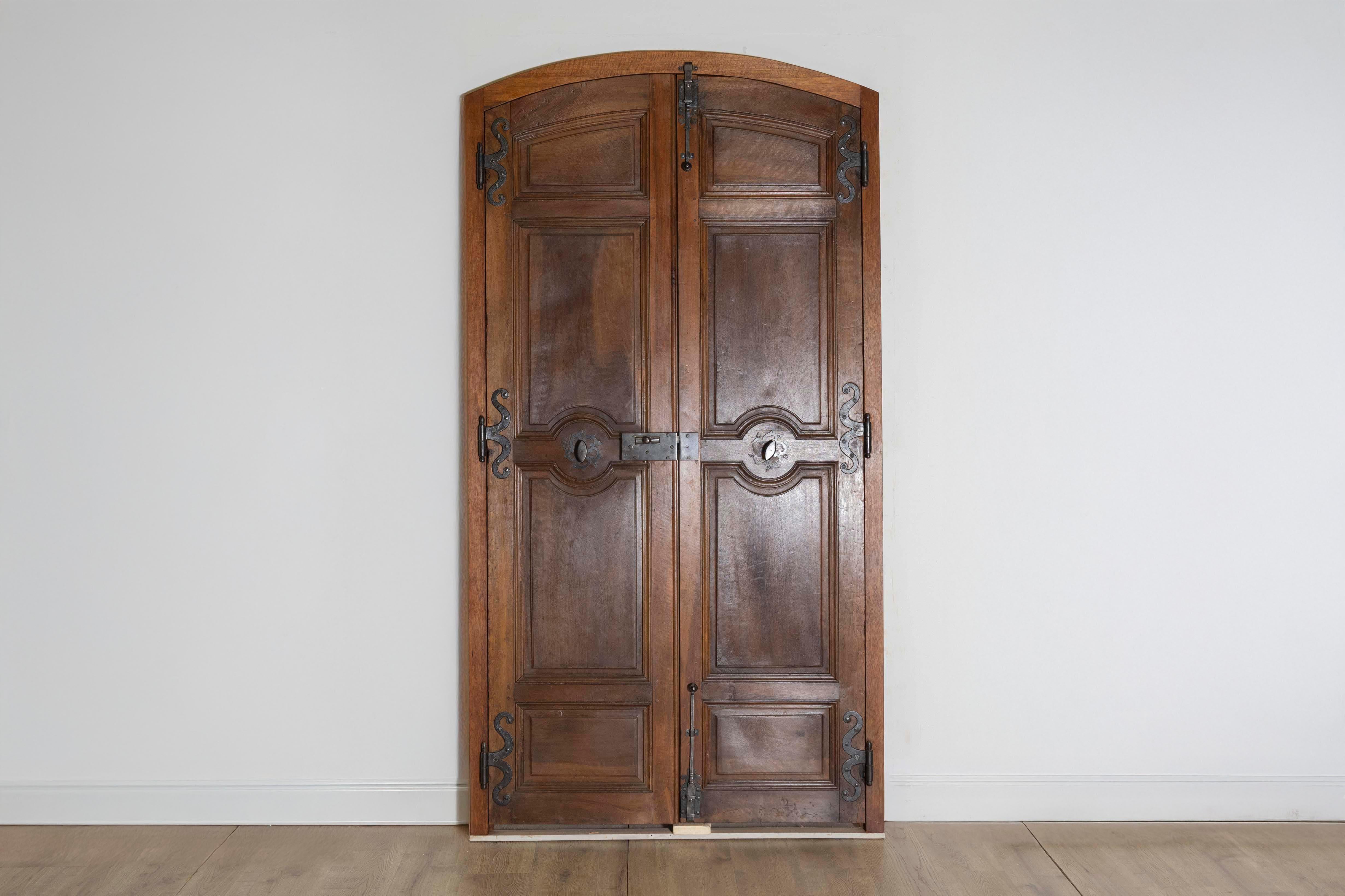 Questa squisita coppia di porte di comunicazione francesi della fine del XVIII secolo, circa 1790, mostra la raffinata maestria tipica dell'epoca. Le porte sono realizzate in legno scuro e ricco, con pannelli intricati e piani graziosamente arcuati