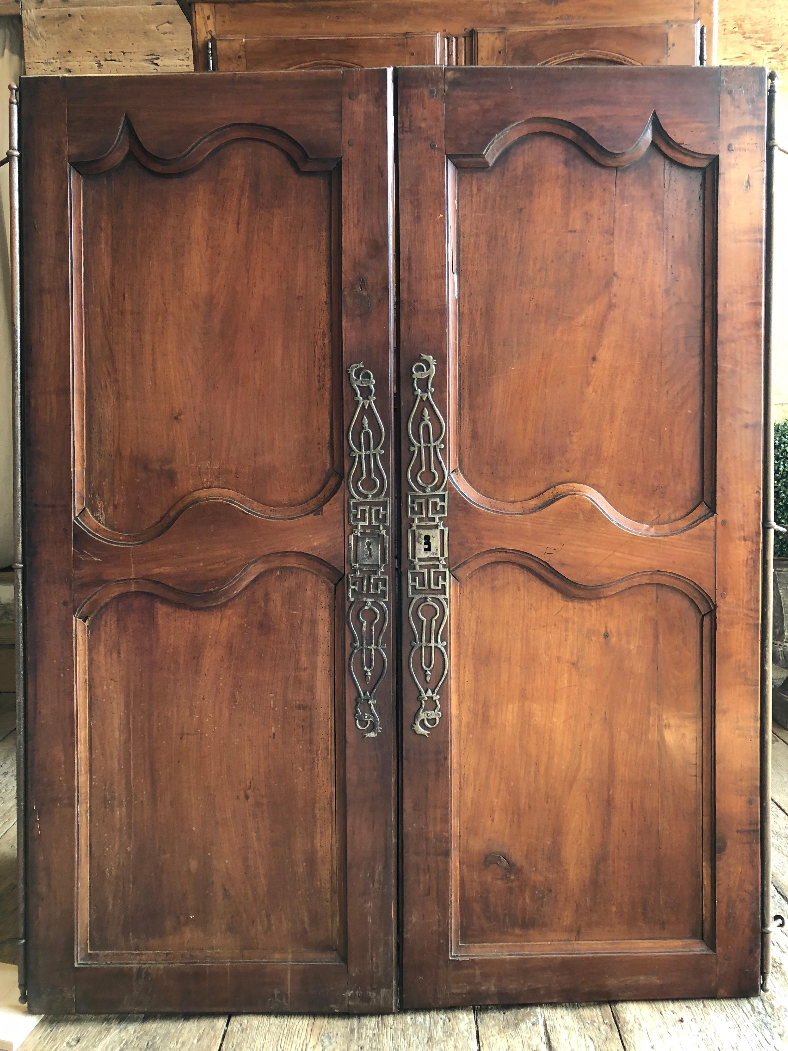 A pair of French Louis XV armoire doors, circa 1760, in cherry, with original steel hardware, nicely paneled and with original lock. Great for adding interest to built-in closets or cabinets.