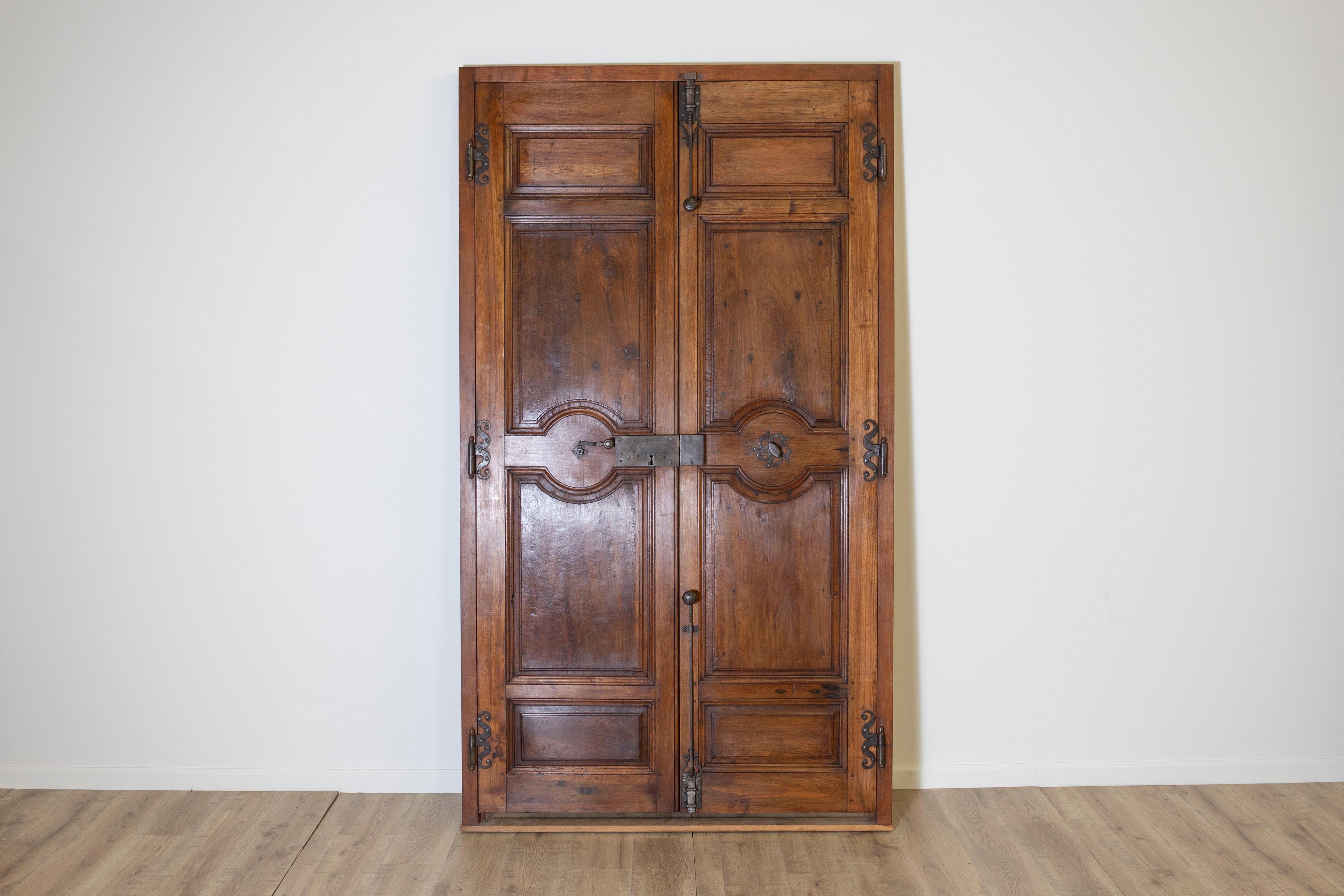 This magnificent pair of 18th-century French double-sided Aix doors originates from Avignon and showcases the timeless craftsmanship of the Louis XV period. Crafted from solid walnut, the doors display a warm, rich patina that highlights the natural