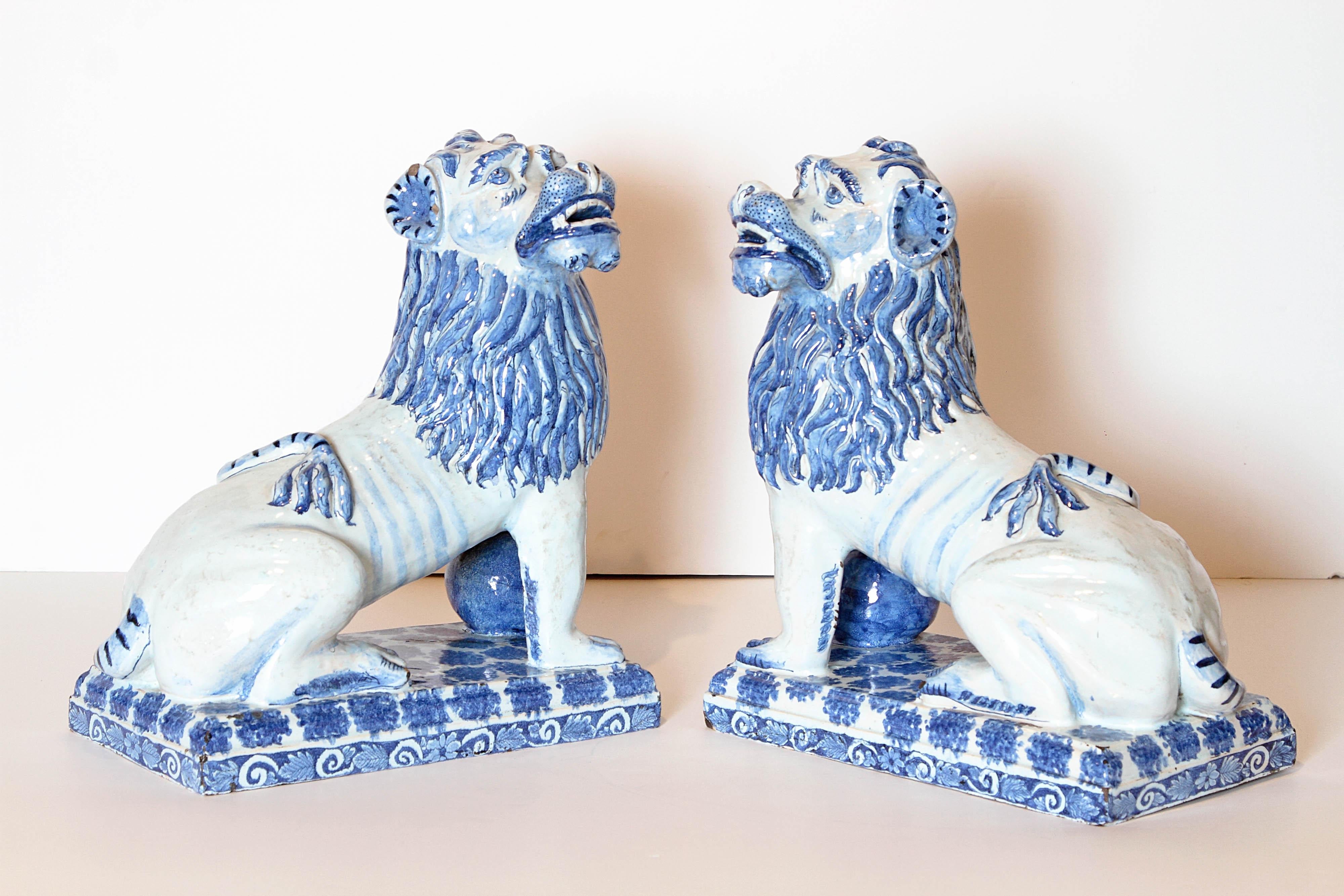 A pair of French faience lions in blue monochrome. Each lion is seated and looking to one side on a rectangular base with great attention to detailing of the manes, ears and snarling faces. Formerly museum owned. One figure has an old staple repair.