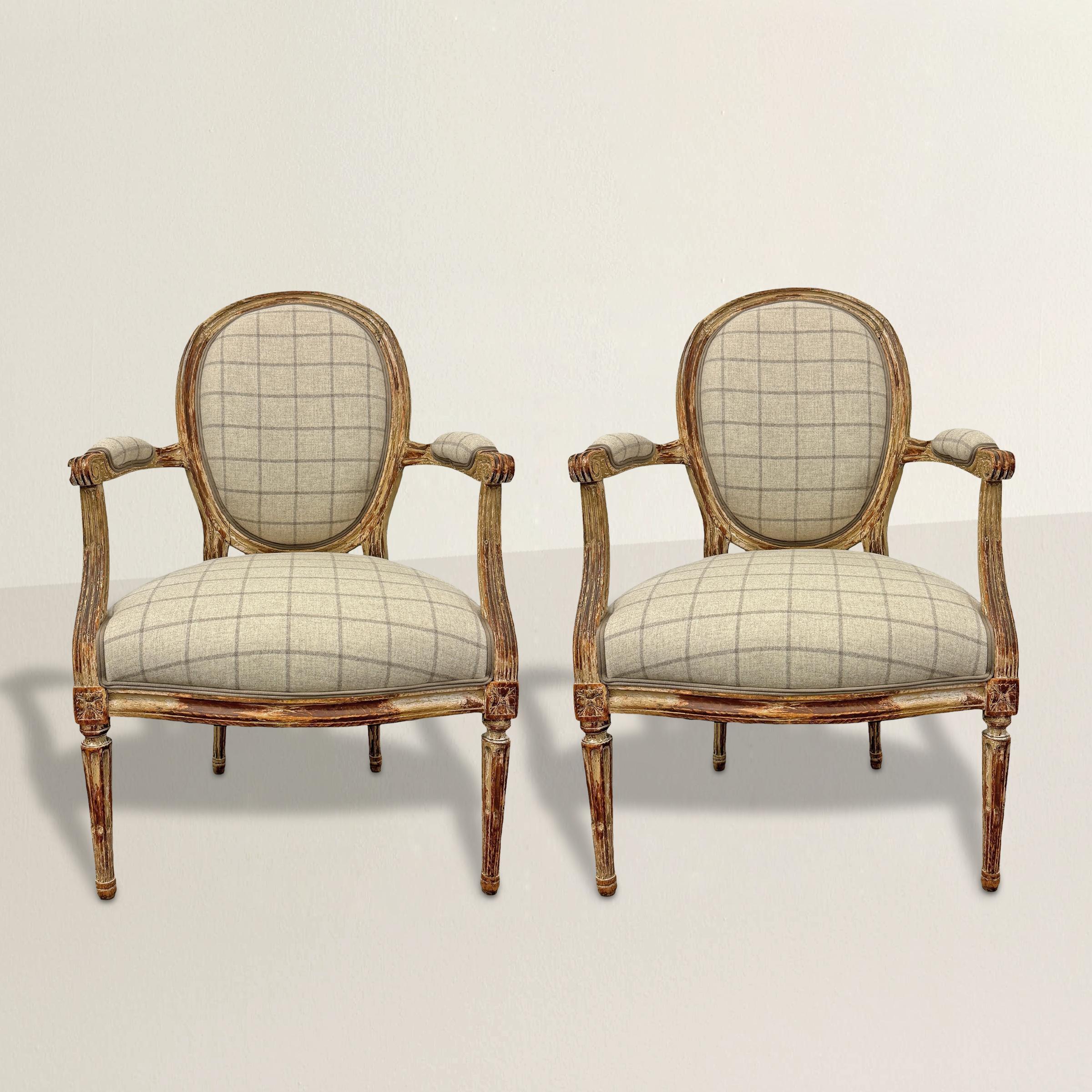 Cette belle paire de fauteuils Louis XVI français du XVIIIe siècle apporte une touche de charme historique avec une touche de fraîcheur et d'espièglerie. Leurs élégants dossiers ovales et leurs accoudoirs droits rembourrés sont soutenus par des