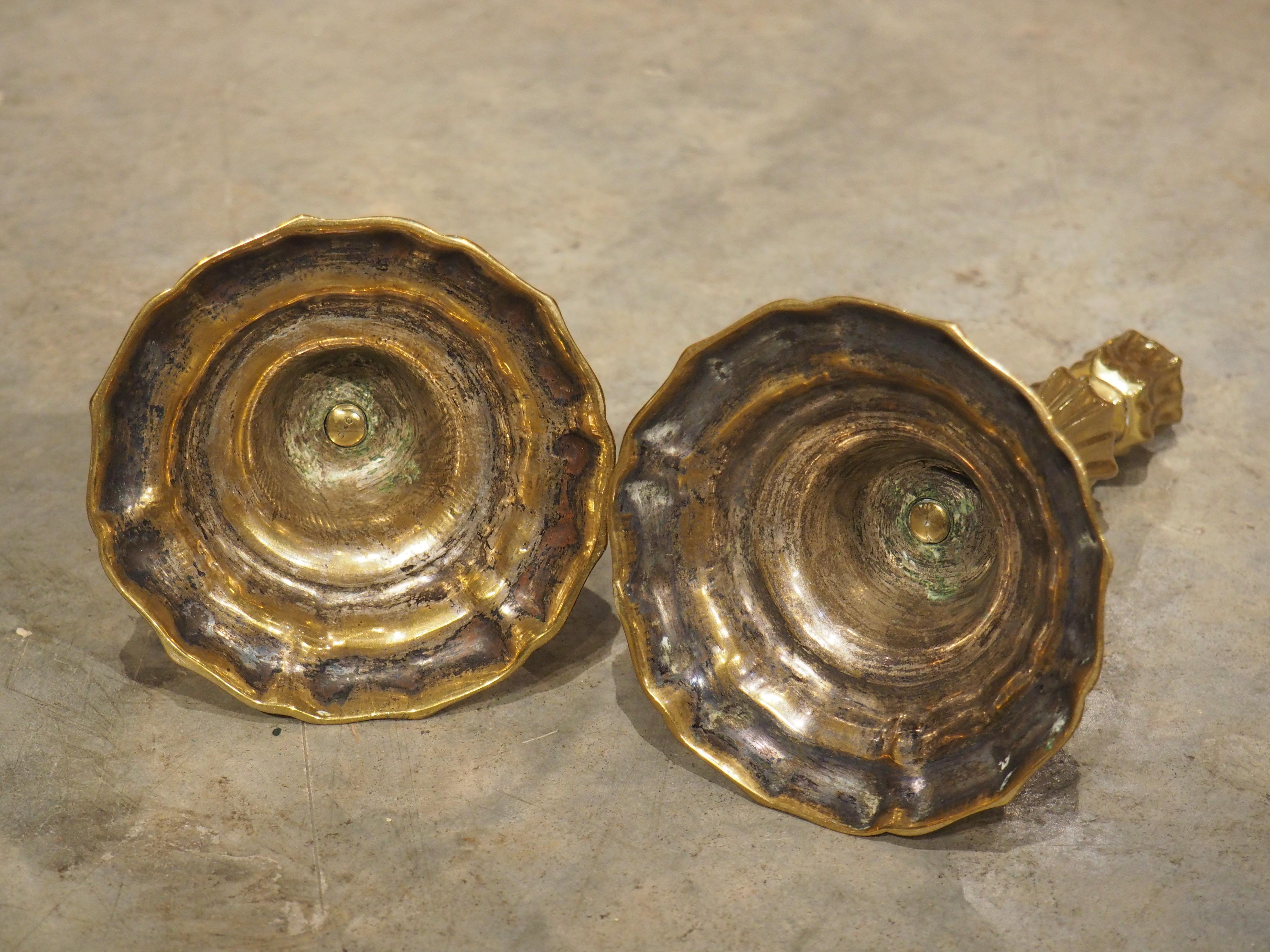 Dieses Paar vergoldeter Bronzeleuchter wurde um 1700 in Frankreich gegossen. Die stark konturierten und geschwungenen Sockel spiegeln sich in den vertieften Lappen wider, die die Schäfte und Kapitelle schmücken und an geschlossene Blütenknospen