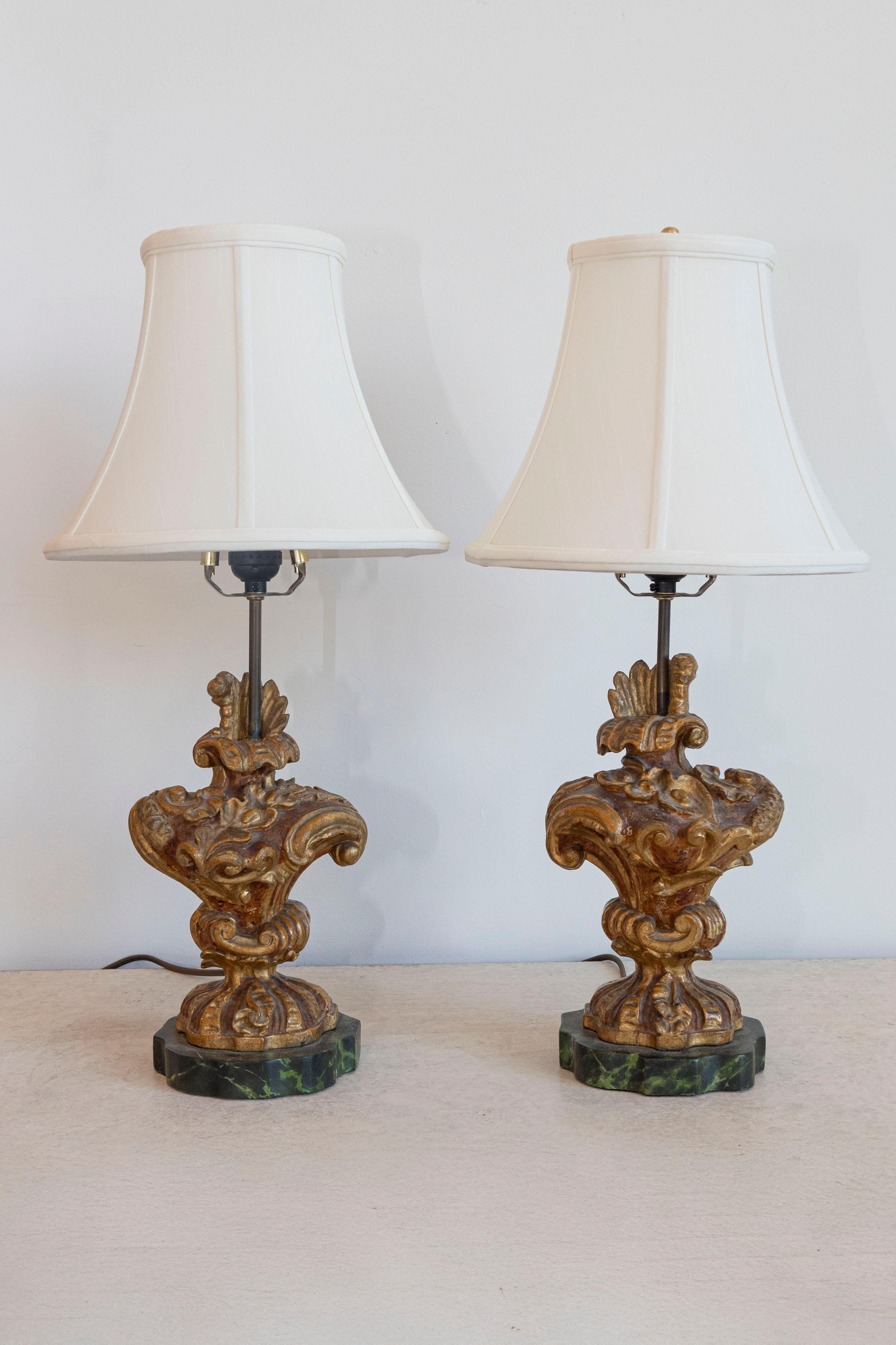 Cette étonnante paire de lampes de table françaises du XVIIIe siècle est fabriquée à partir de fragments architecturaux en bois doré, reconvertis en d'élégantes pièces d'éclairage. Les fragments présentent des sculptures rococo élaborées, notamment
