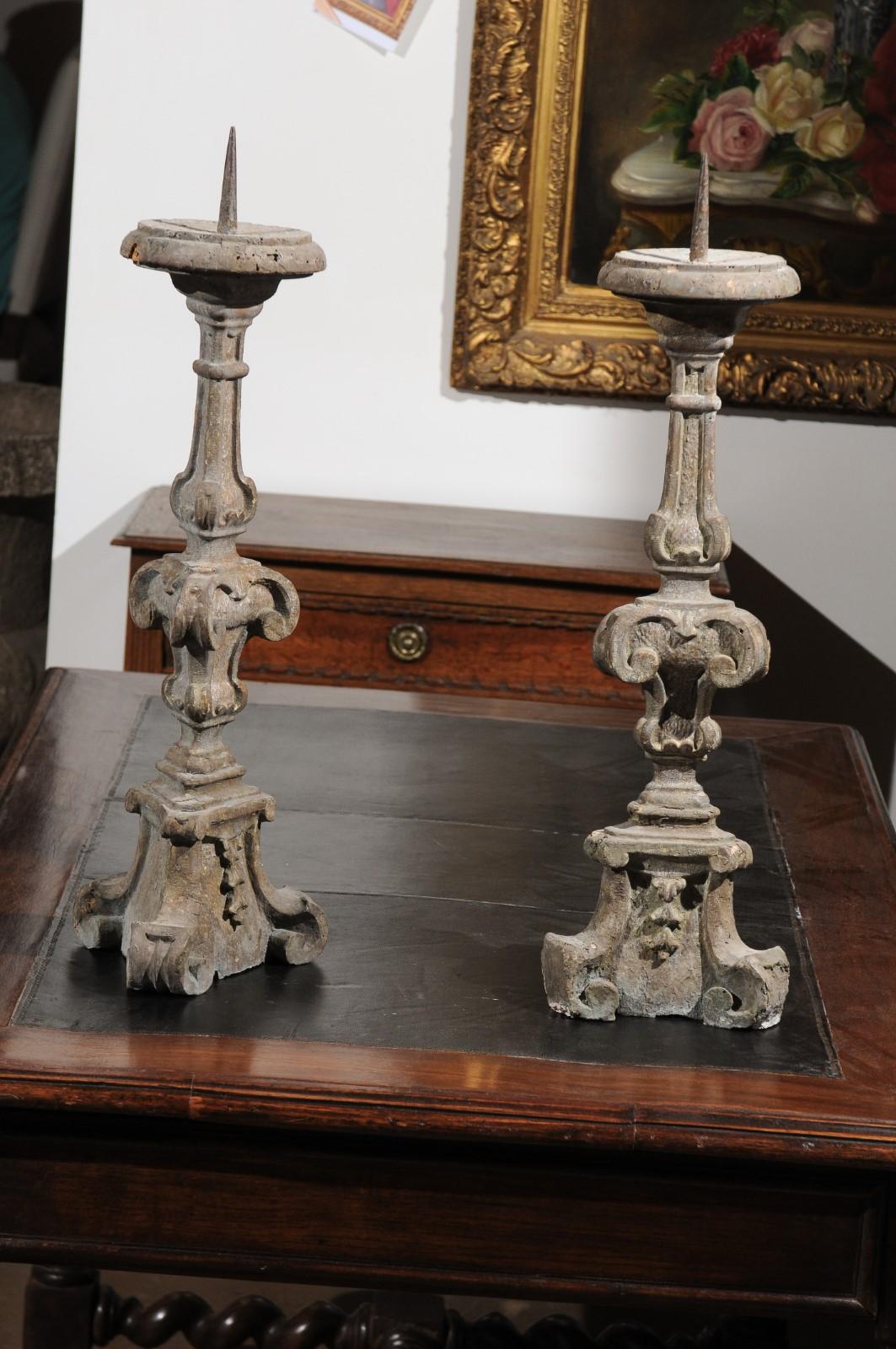 A pair of French 18th century painted and carved wooden altar sticks with volutes and delicate foliage. Born in France during the later years of King Louis XV's reign, each of this pair of altar sticks is painted in a light grey color complimenting