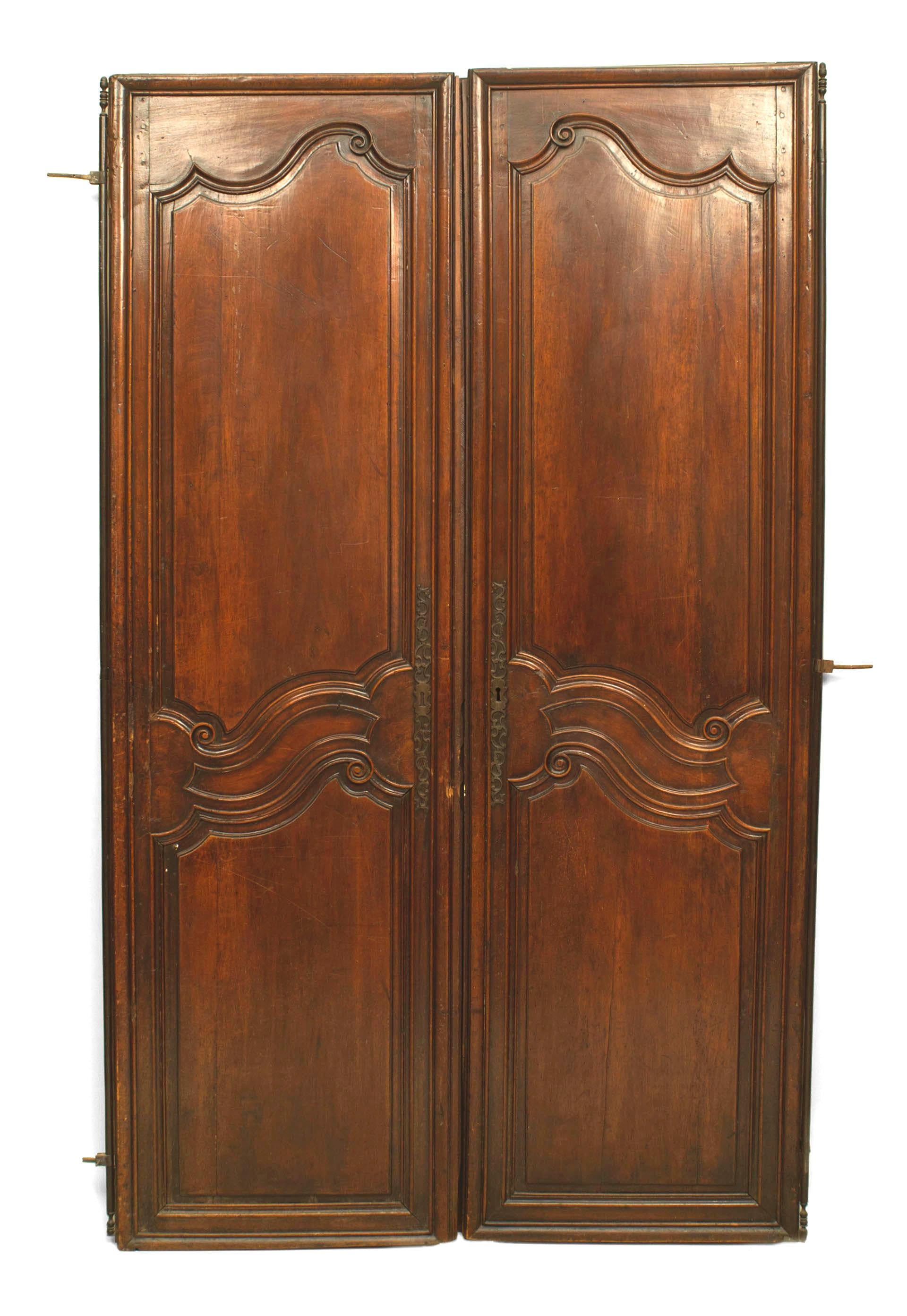 Pair of French Provincial (18th Century) walnut doors with 2 panels with scroll carving and wrought iron hardware (PRICED AS Pair).
