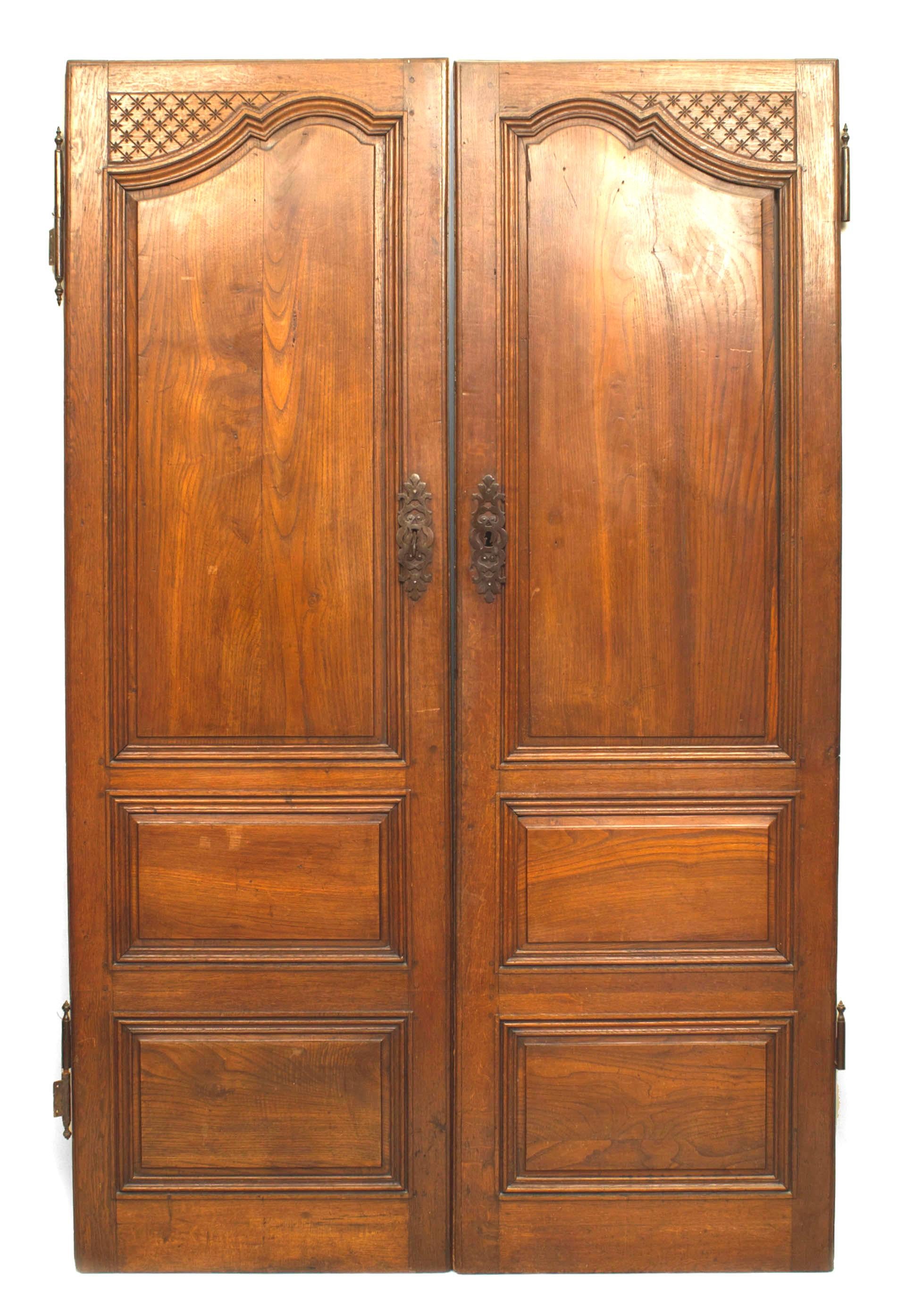 Pair of French Provincial (18th Century) walnut doors with 2 small rectangular panels under a large one with carving in corner and wrought iron hardware, finished back. (PRICED AS Pair).
