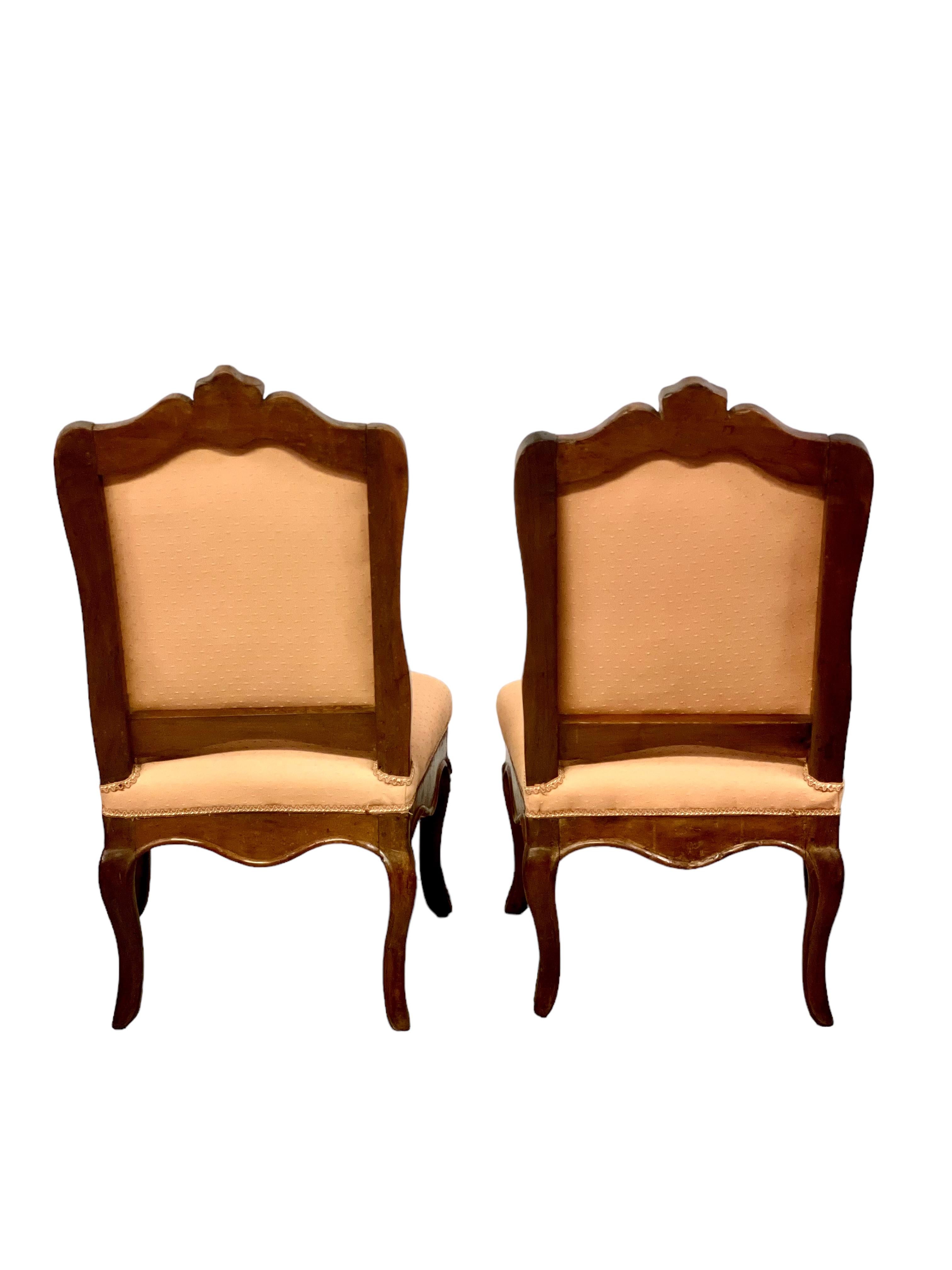 A wonderful and rare pair of sculpted Regency slipper chairs in beech, believed to date from around 1720, and raised on four cabriole legs. 
These supremely comfortable chairs feature shaped,padded backs and seats, beautifully upholstered in