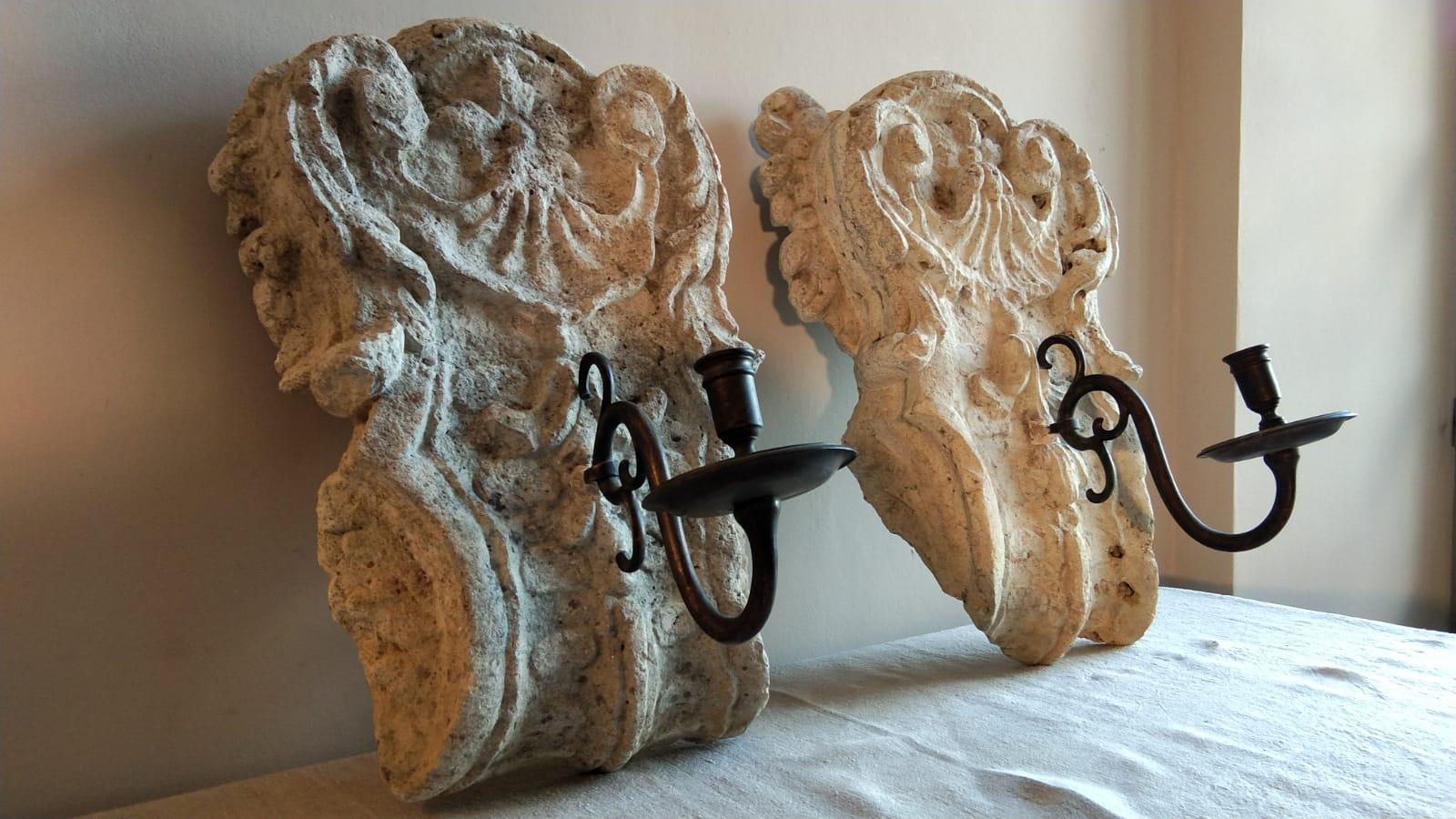 A pair of French stone sconces from the 18th century with bronze arms.