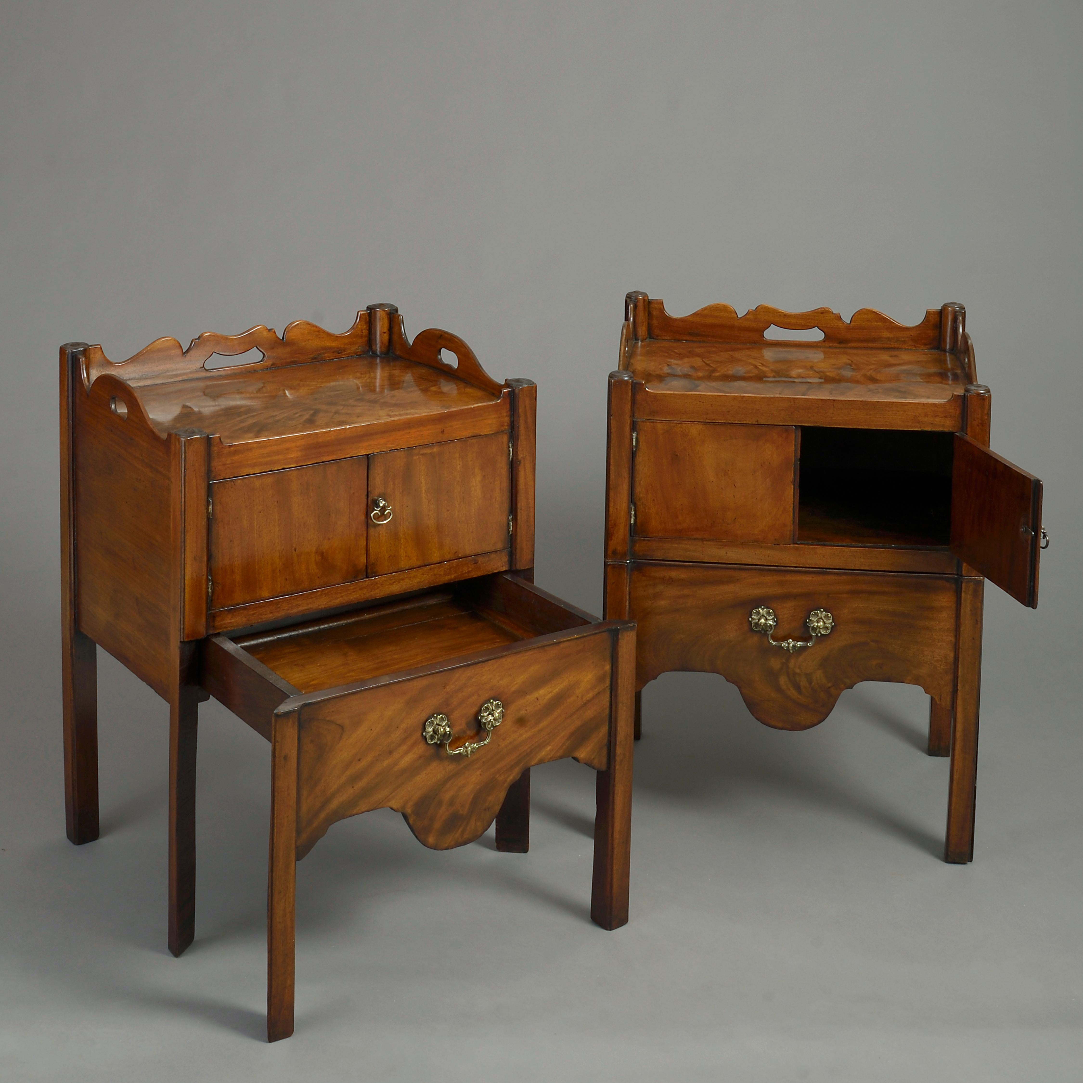 A pair of mid-18th century George III period mahogany bedside commodes or night stands, each having a finely figured galleried top with pierced carrying handles above two cupboard doors, the lower section with shaped apron, opening to reveal a