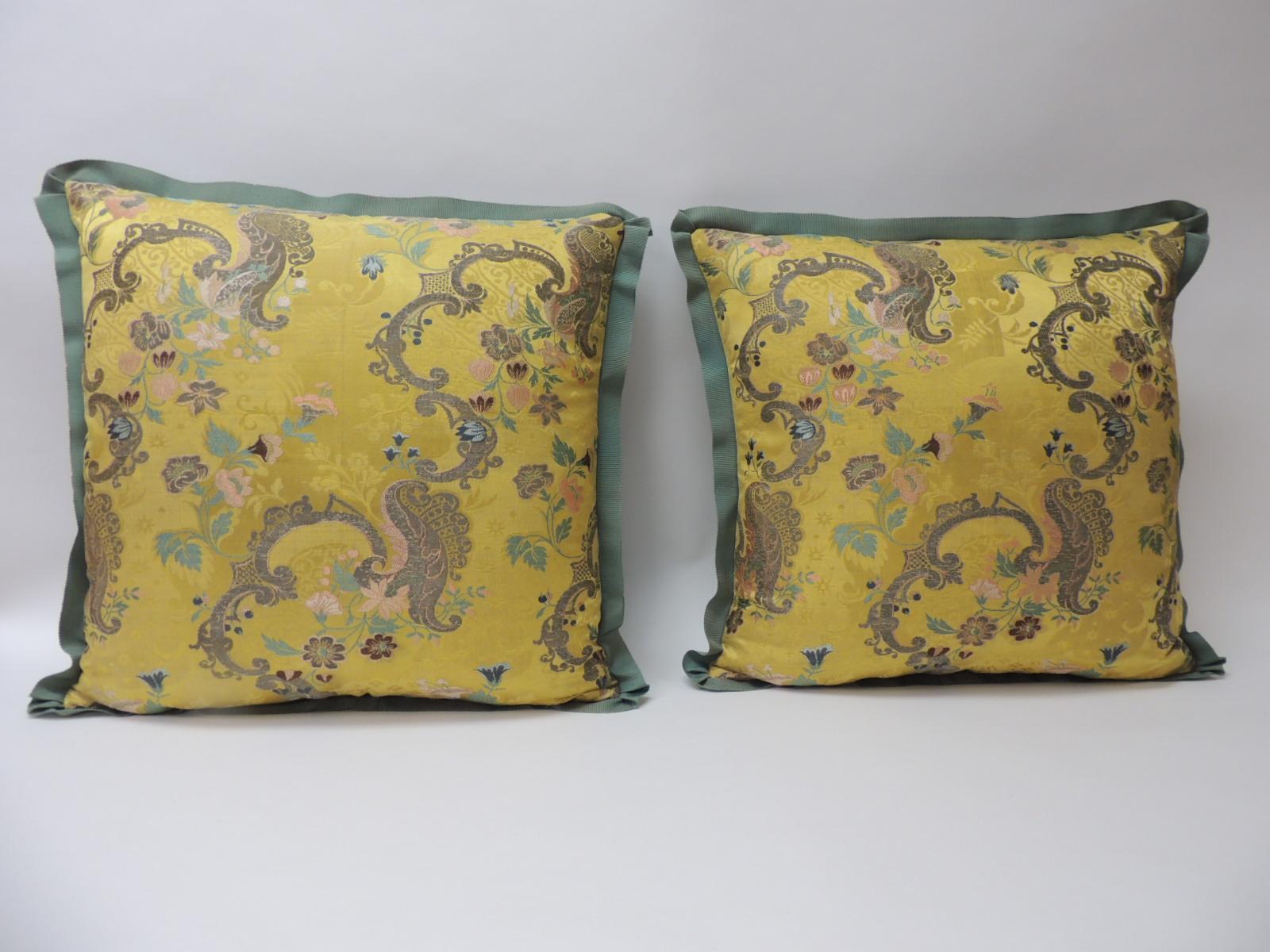 Pair of 18th century green and gold brocaded French silk decorative pillows. Antique textile embroidered with silk and gold metallic threads. Floral pattern depicting flowers in bloom. Strié green silk backings. Embellished with a green French silk
