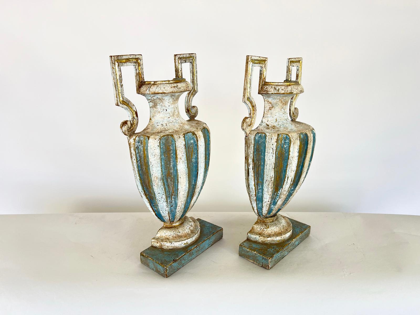 Pair of divided urns, once whole, Neoclassical period, of carved wood with distressed, painted finish;  each having fluted body and square handles, on round foot and rectangular plinth.