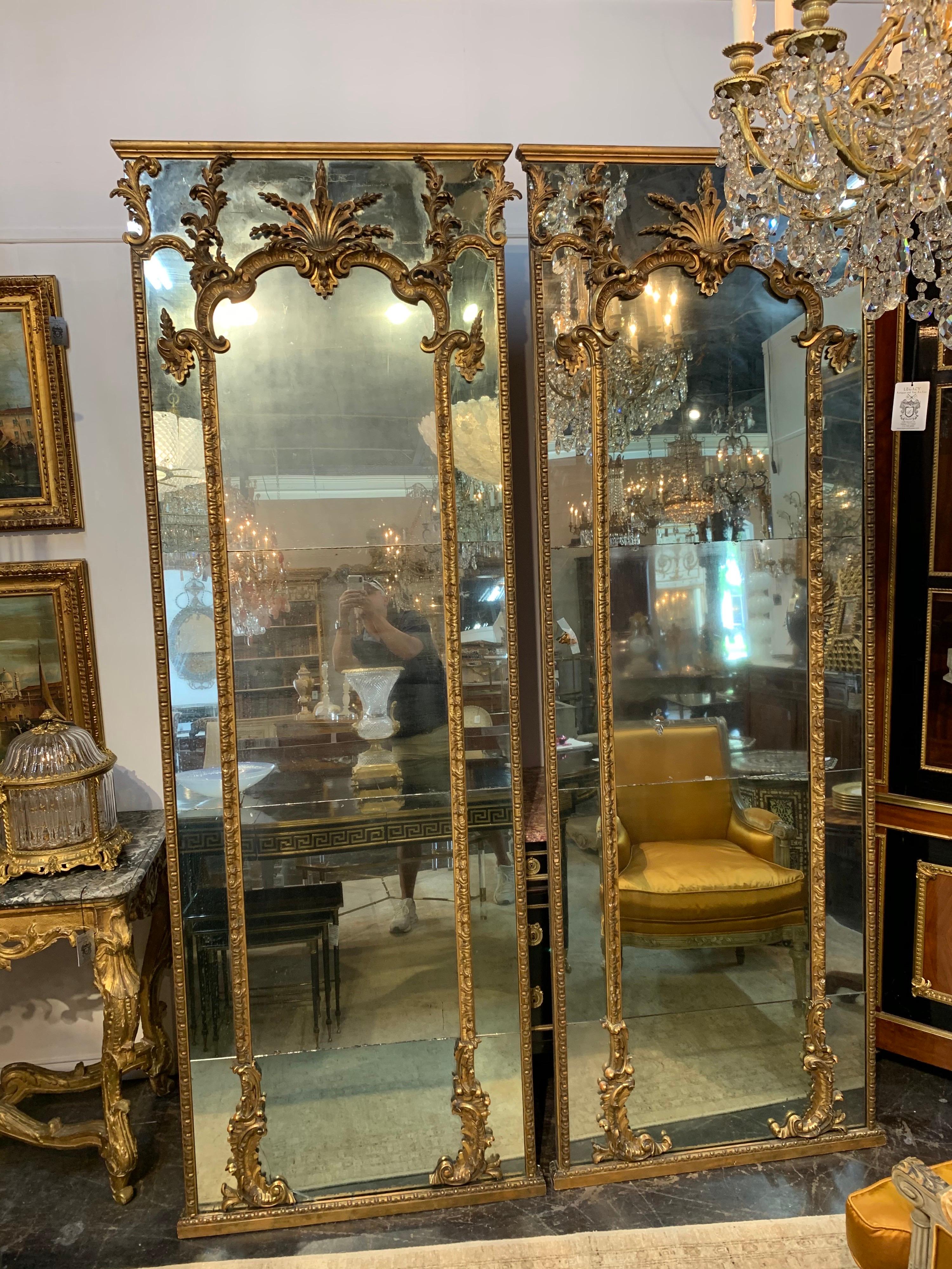 Fabulous pair of 18th century Italian carved and giltwood floor mirrors. Featuring divided panels of original mercury glass. Nice giltwood carvings as well. These create an absolutely a stunning image! Note: There is a small crack in the glass on