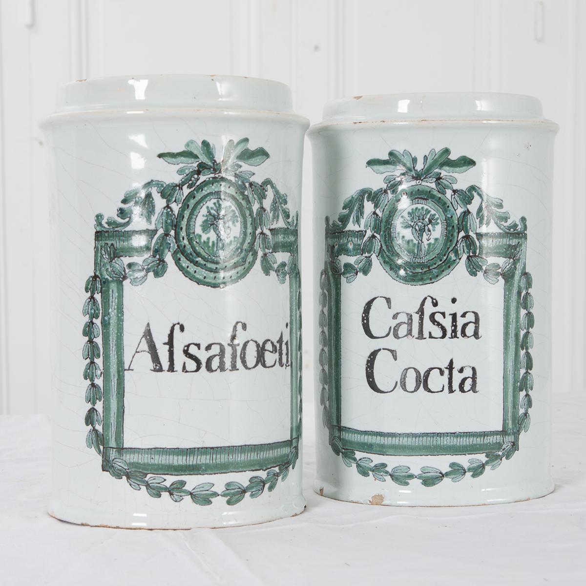 A gorgeous pair of Italian painted faïence storage jars, once used in a French pharmacy, with the names of their contents hand-painted on their fronts. This beautiful pair of jars dates to the end of the 18th century, having been made circa 1780.