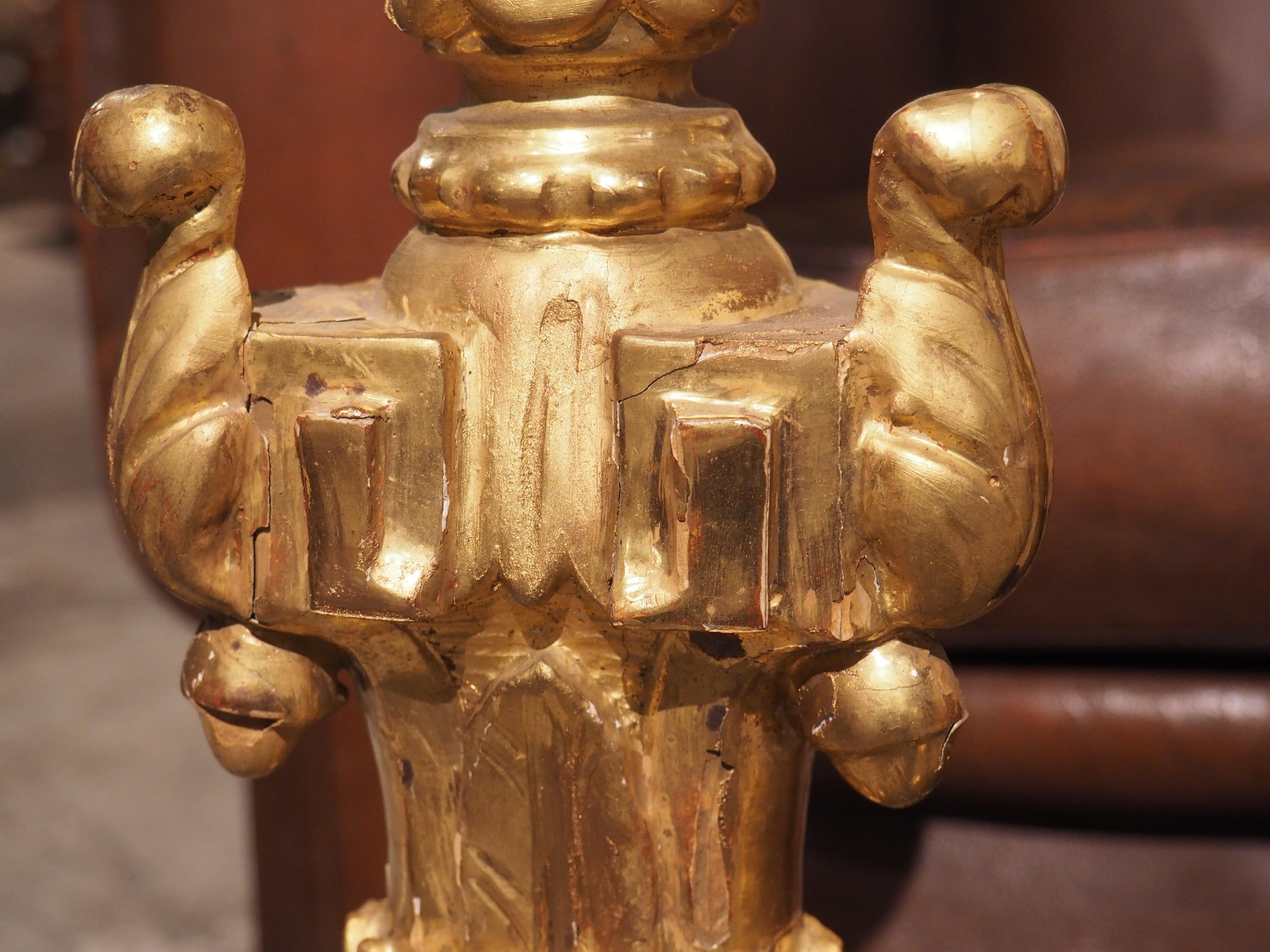 This pair of stunning 18th century candlesticks from Italy features bountiful hand-carved foliate and floral details. The candlesticks sit on a tripartite base, with the form continuing throughout the giltwood columns, indicating that they once